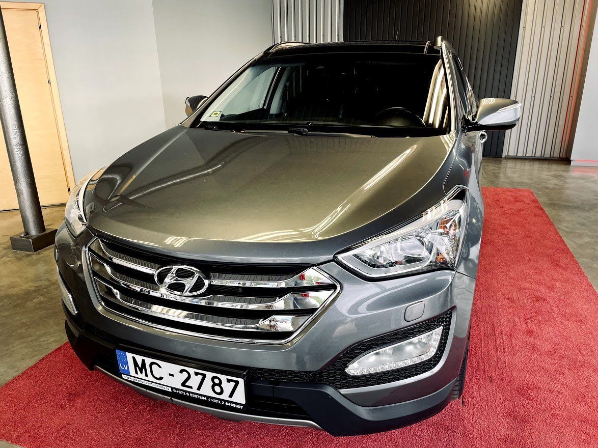 Pelēka hyundai santa fe ir novietota uz sarkana paklāja izstāžu zālē.