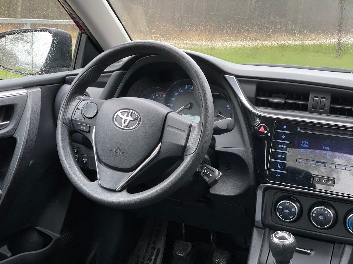 Toyota automašīnas salons ar stūri un instrumentu paneli.