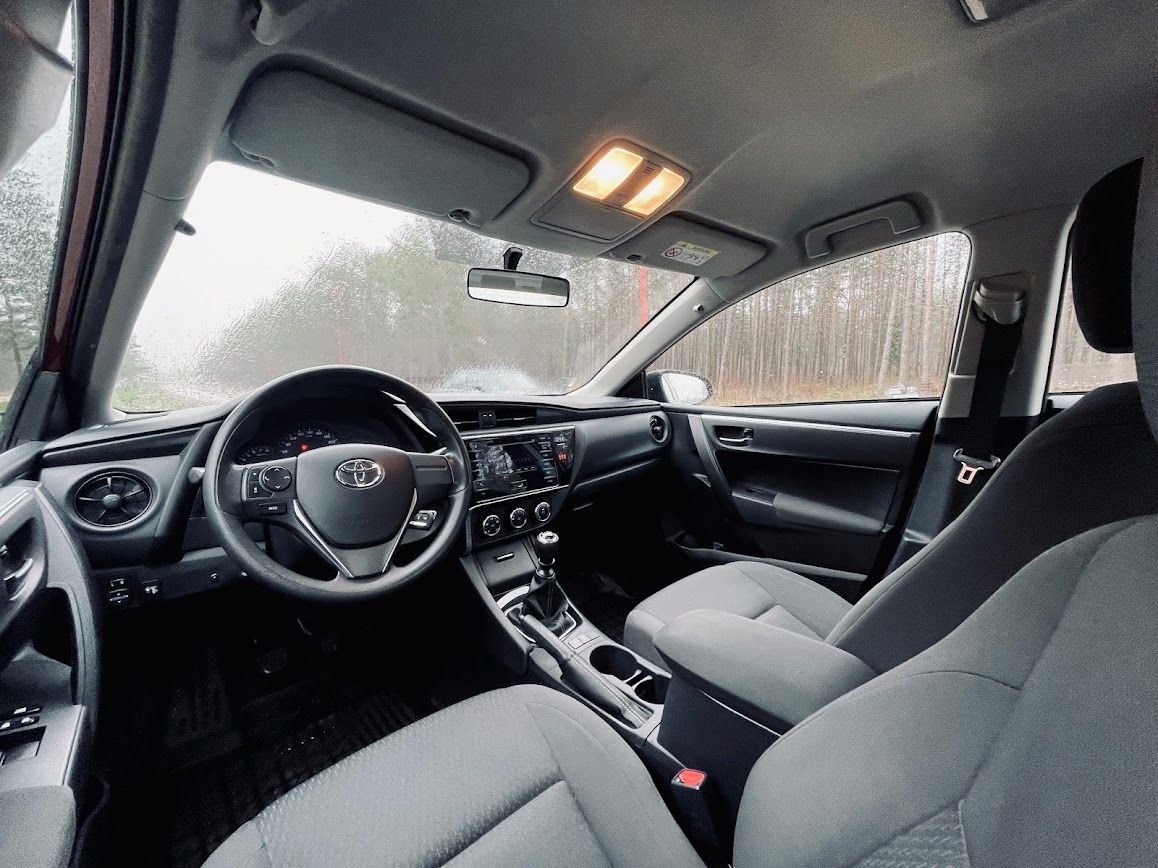 Toyota Corolla salons ar pelēkiem sēdekļiem un stūri.