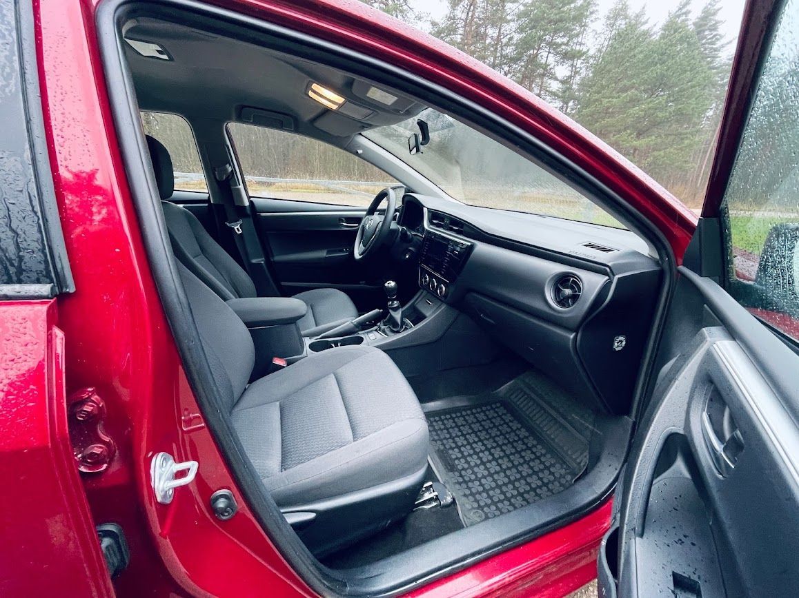 Sarkanas automašīnas iekšpuse ar atvērtām durvīm.