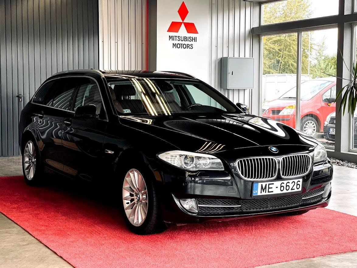 Melns bmw stāv mitsubishi salonā.