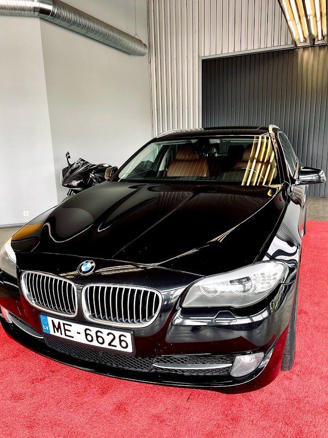 Melns bmw ir novietots uz sarkana paklāja salonā.