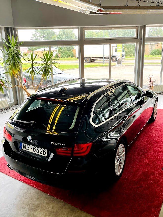 Melna automašīna ir novietota uz sarkanā paklāja salonā.