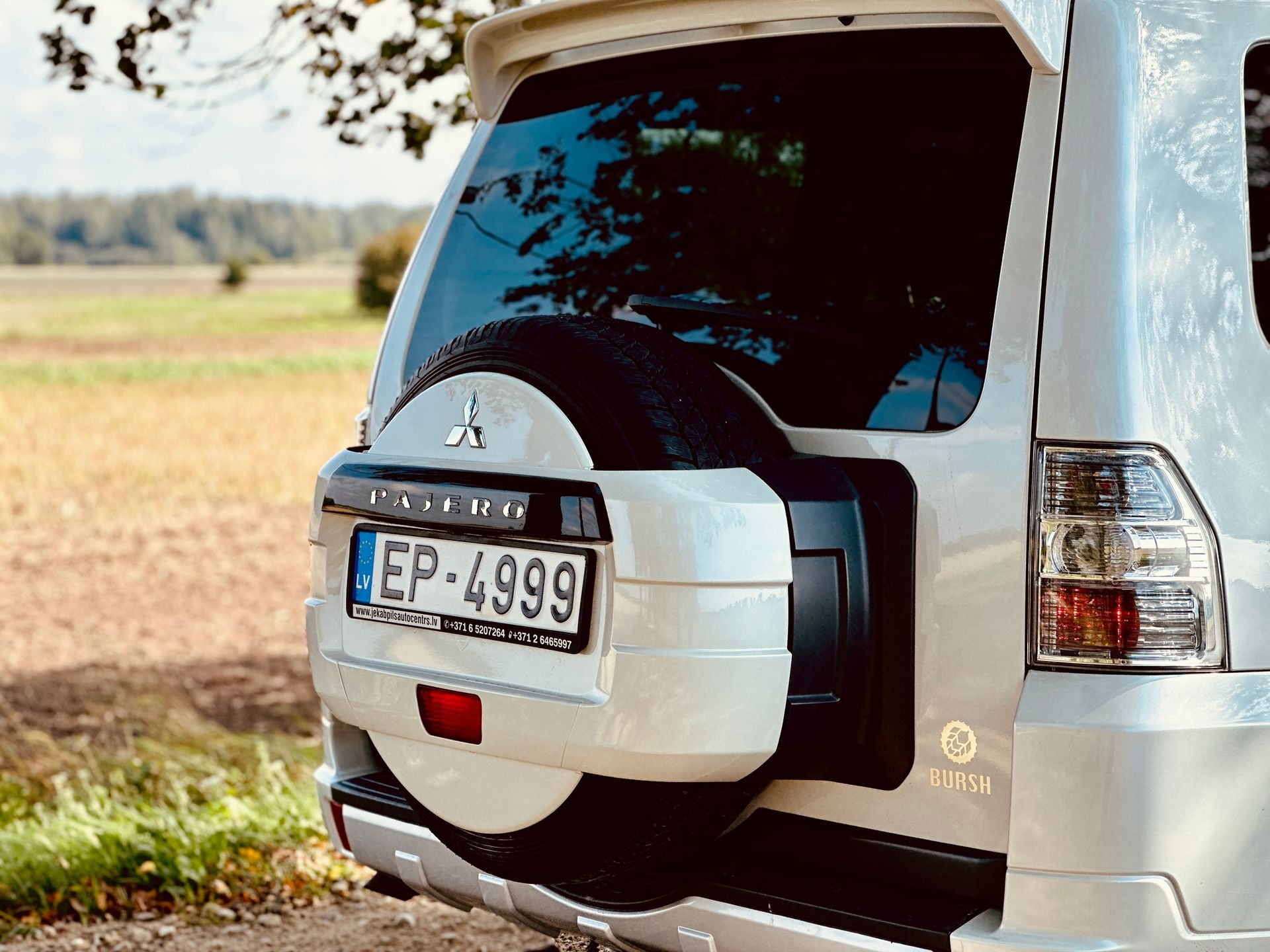 Balts mitsubishi pajero ir novietots laukā.