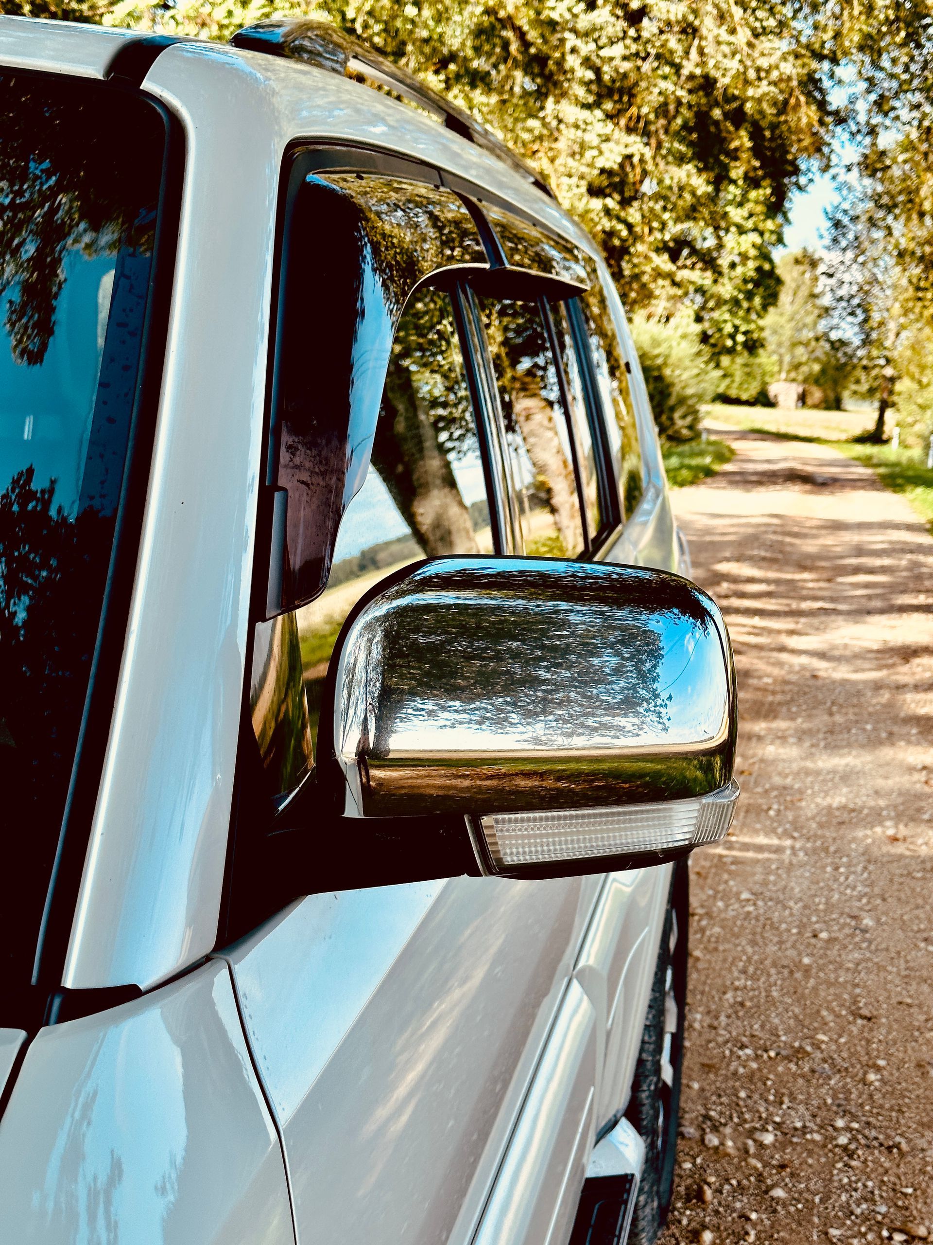 Zemes ceļa malā stāv balts apvidus auto.