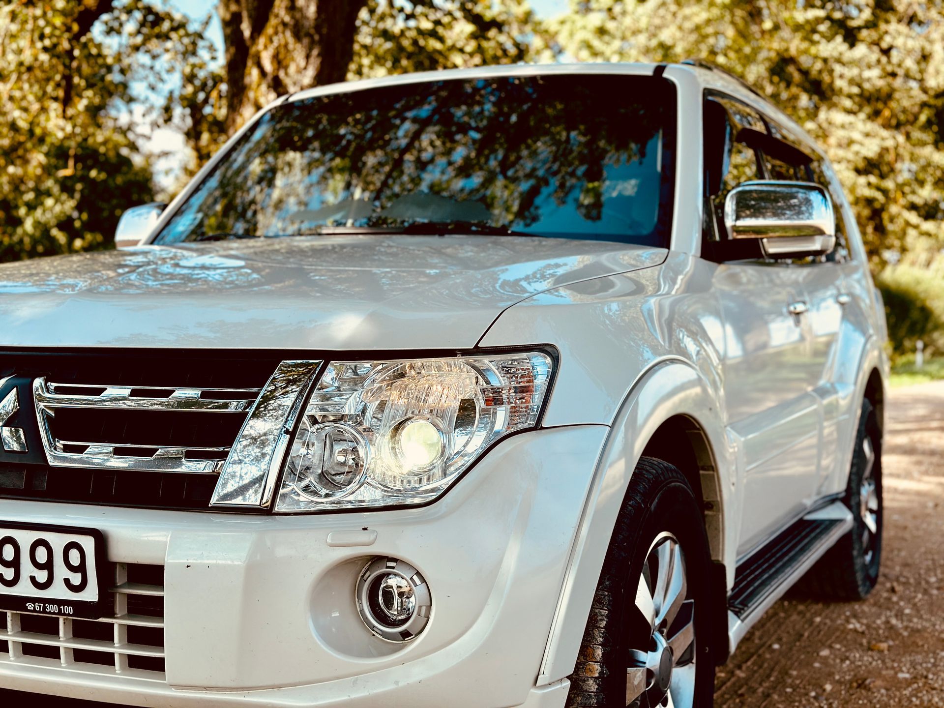 Balts mitsubishi pajero ir novietots uz zemes ceļa.