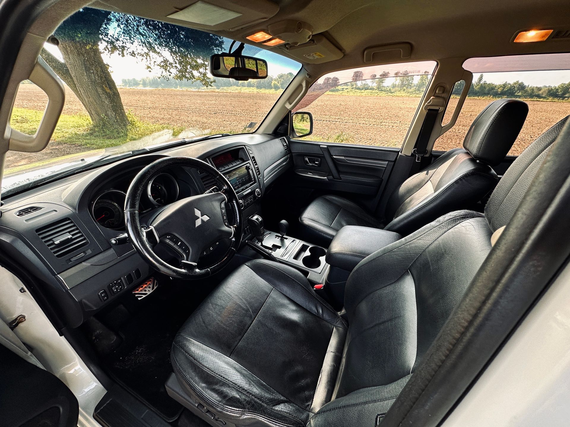 Balta mitsubishi pajero interjers ar melniem ādas sēdekļiem