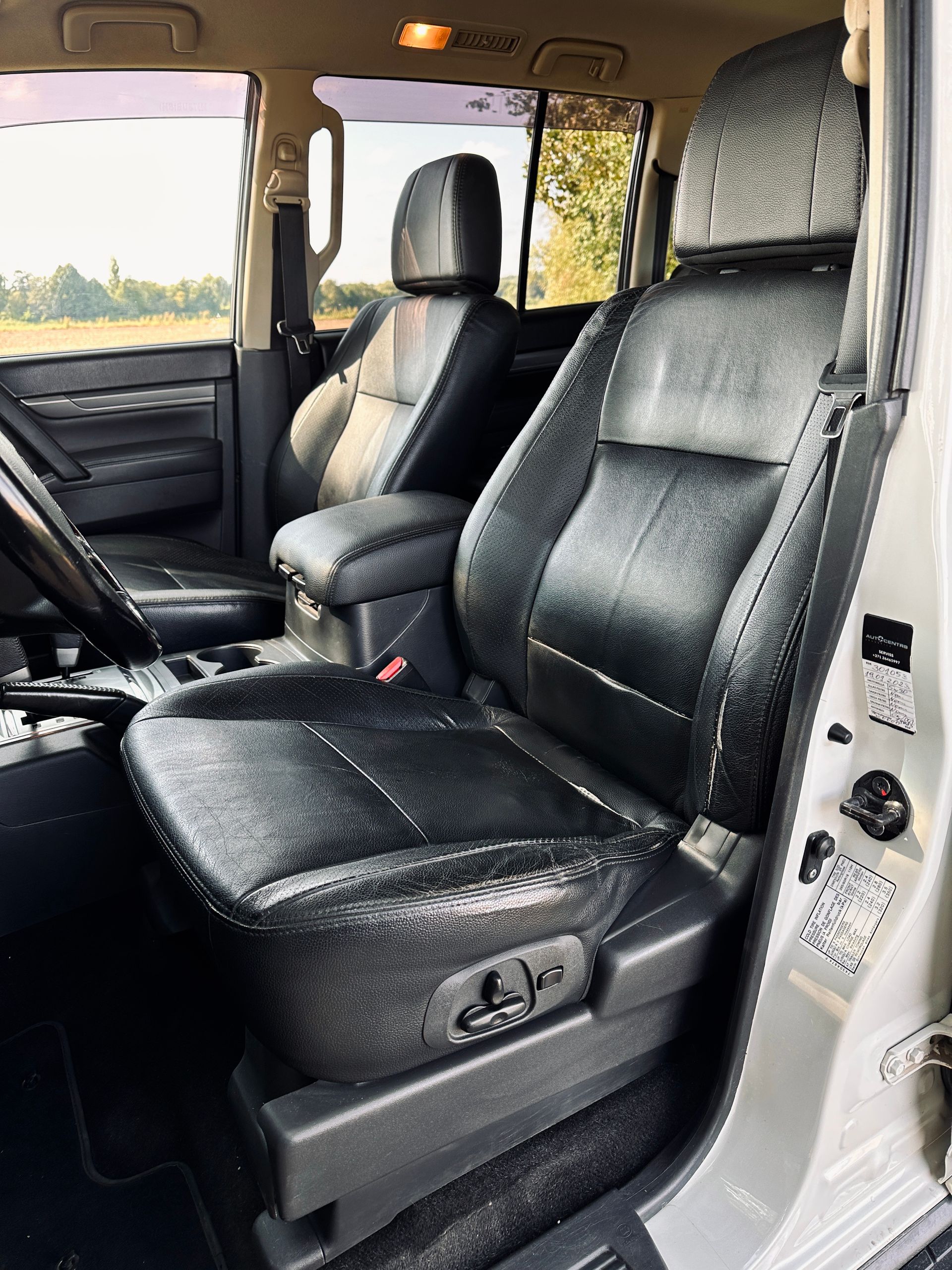 Automašīnas iekšpuse ar melniem ādas sēdekļiem un stūri.