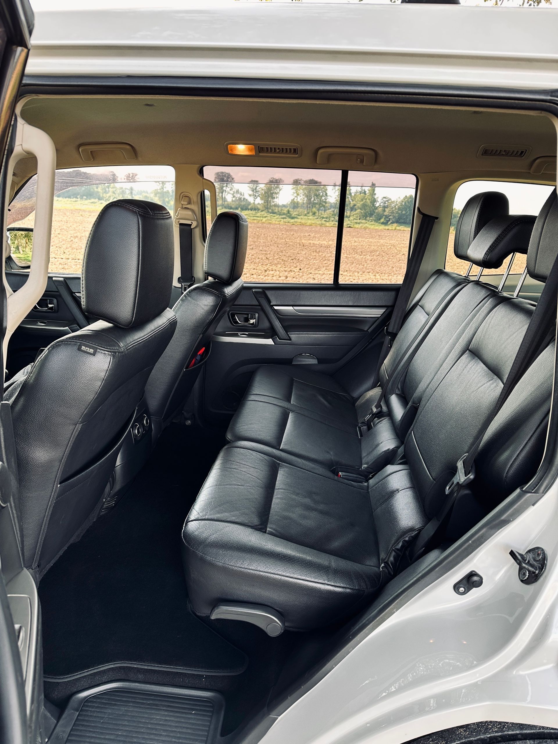 Baltas automašīnas aizmugurējais sēdeklis ar melniem ādas sēdekļiem.