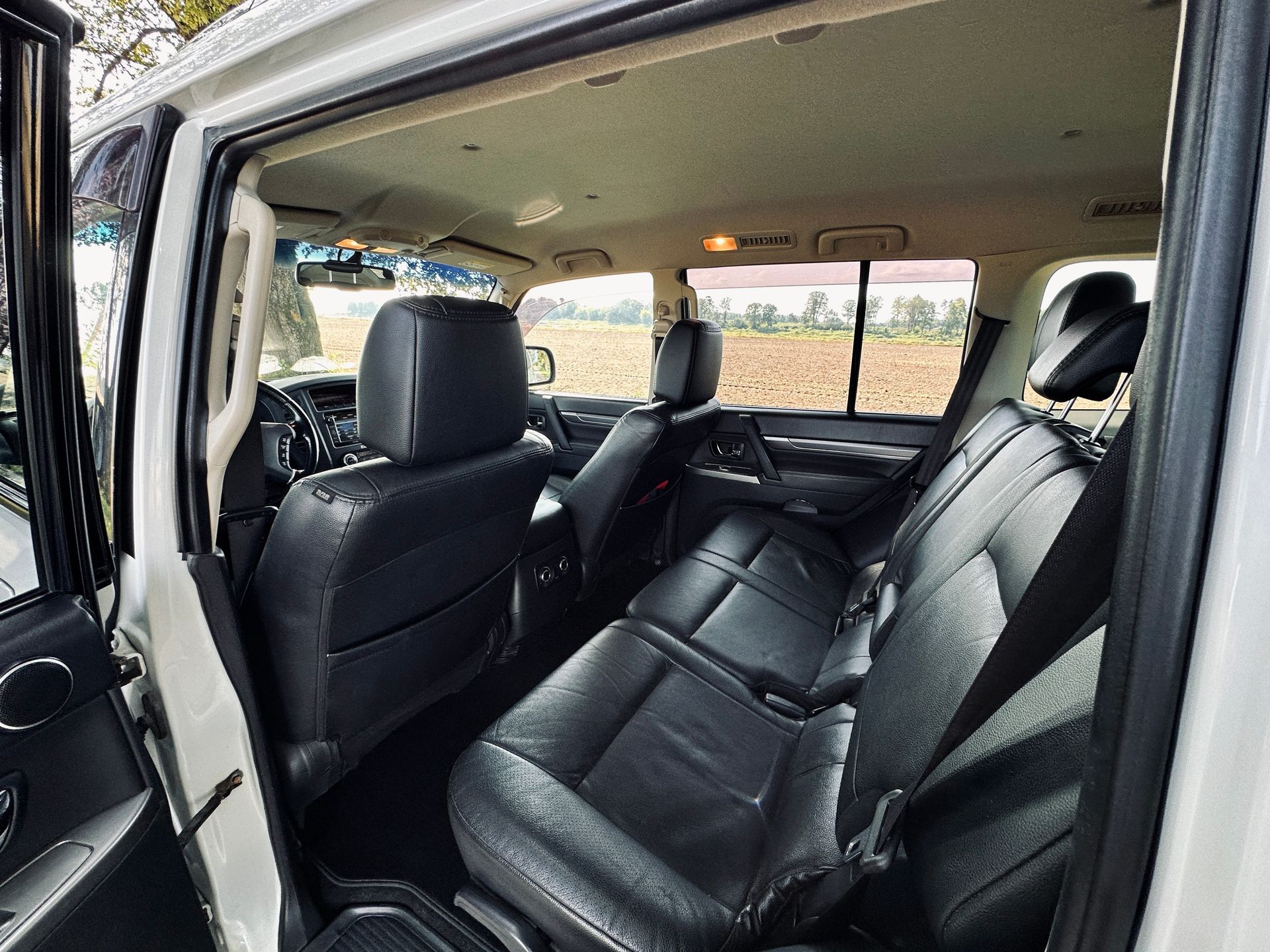 Baltas automašīnas aizmugurējais sēdeklis ar melniem ādas sēdekļiem.