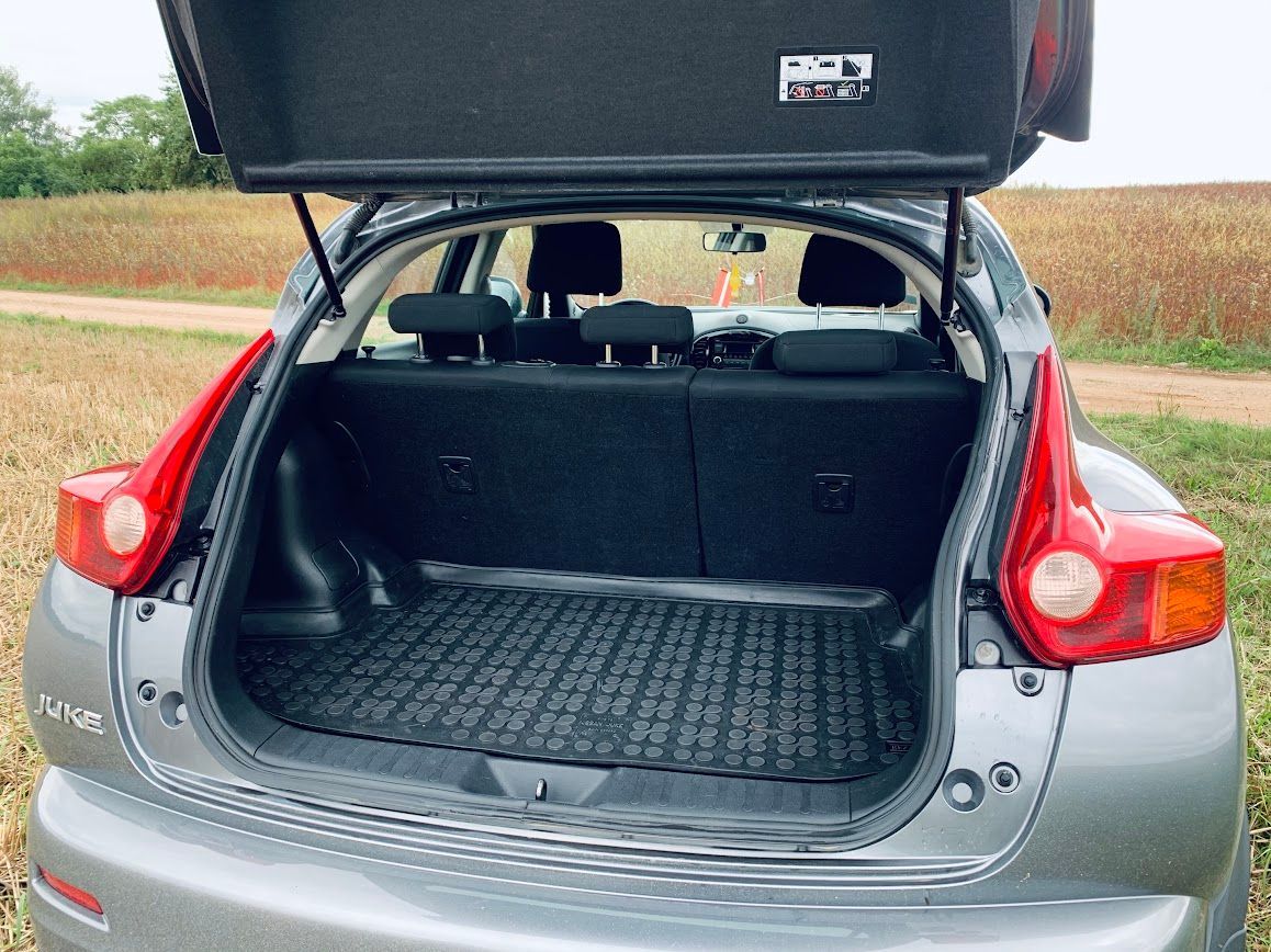 Sudraba auto ar atvērtu bagāžnieku stāv laukā.