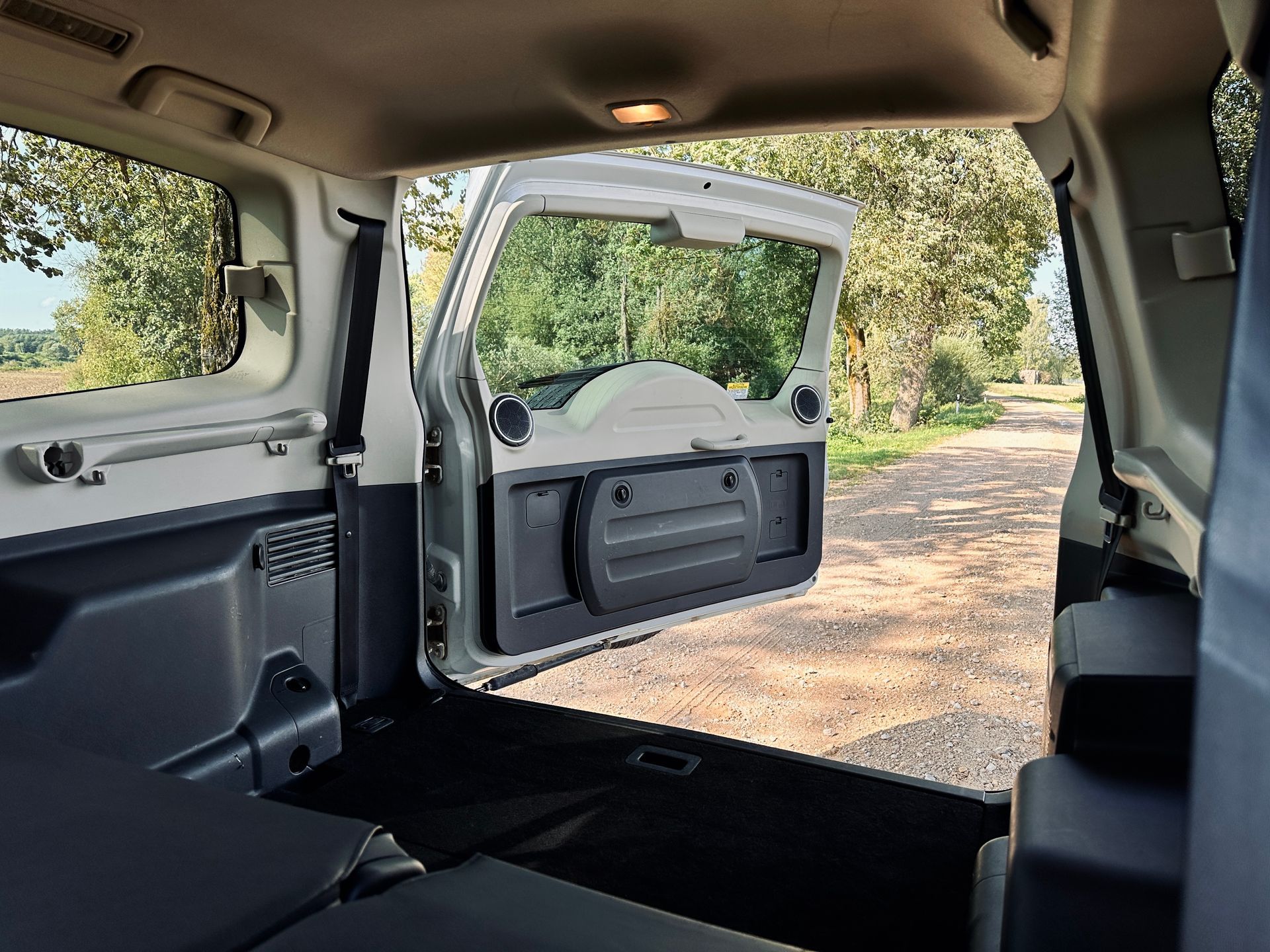 Automašīnas aizmugurējās durvis ir atvērtas un bagāžnieks ir atvērts.