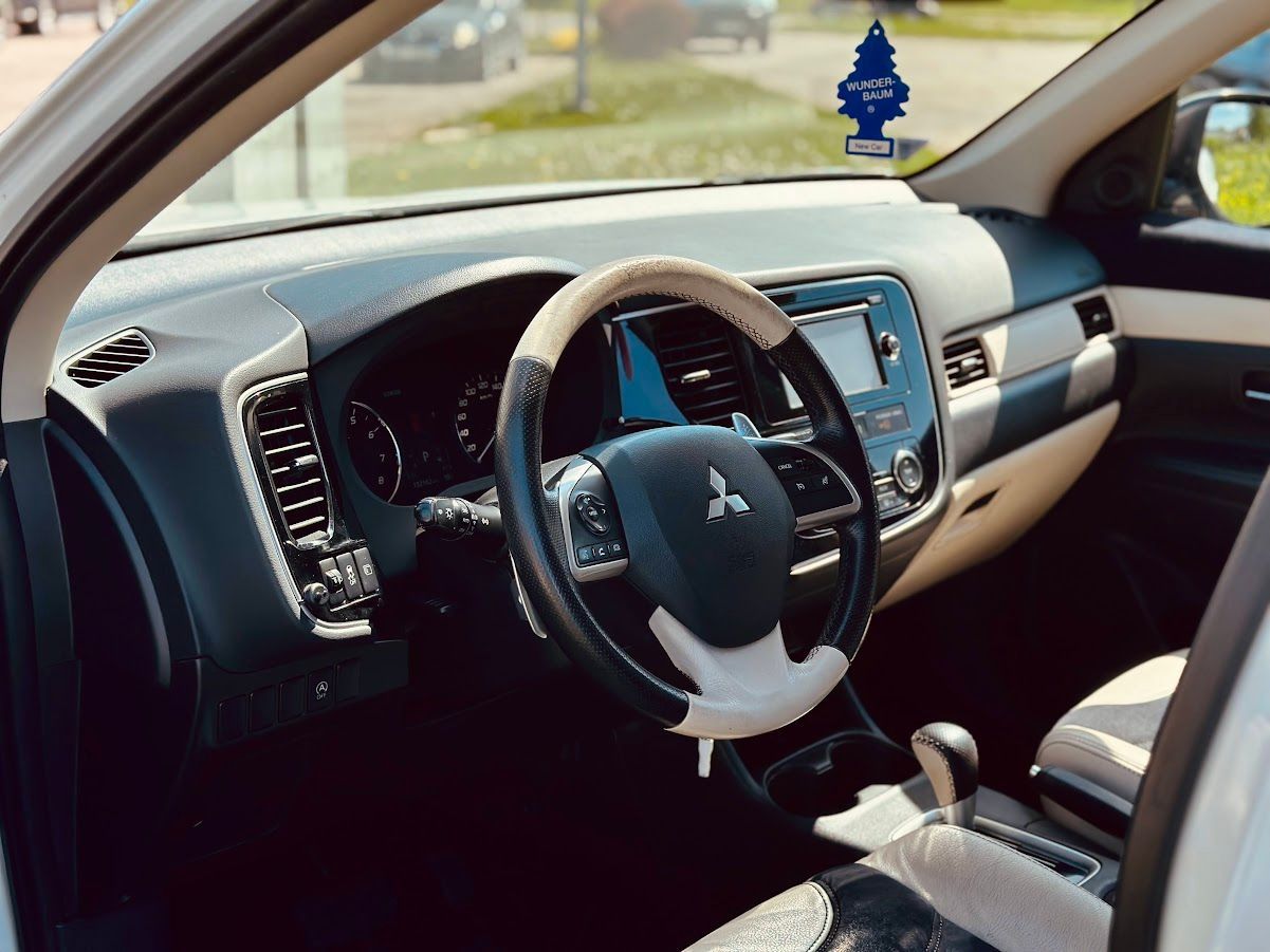 Balta mitsubishi outlander interjers ar nelielu koka uzlīmi uz loga
