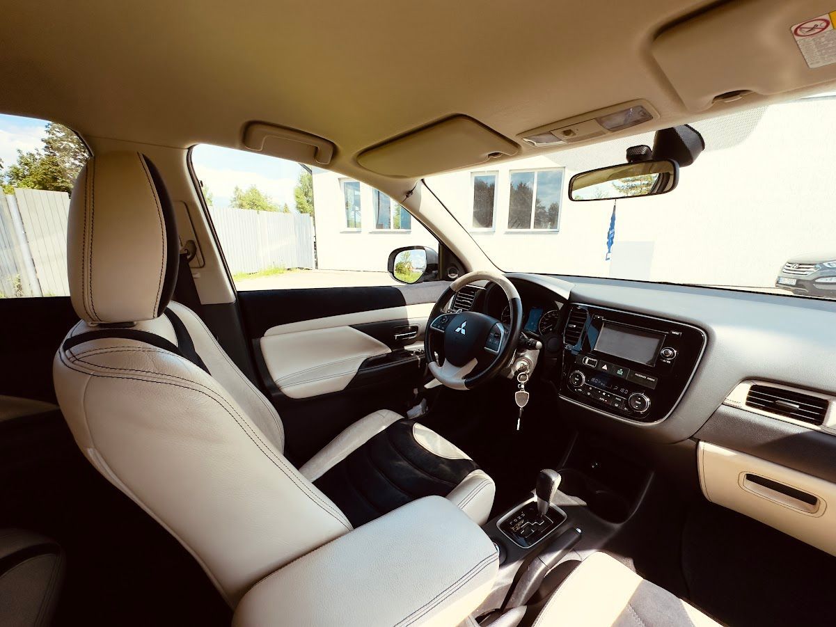 Automašīnas salons ar baltiem sēdekļiem un stūri.