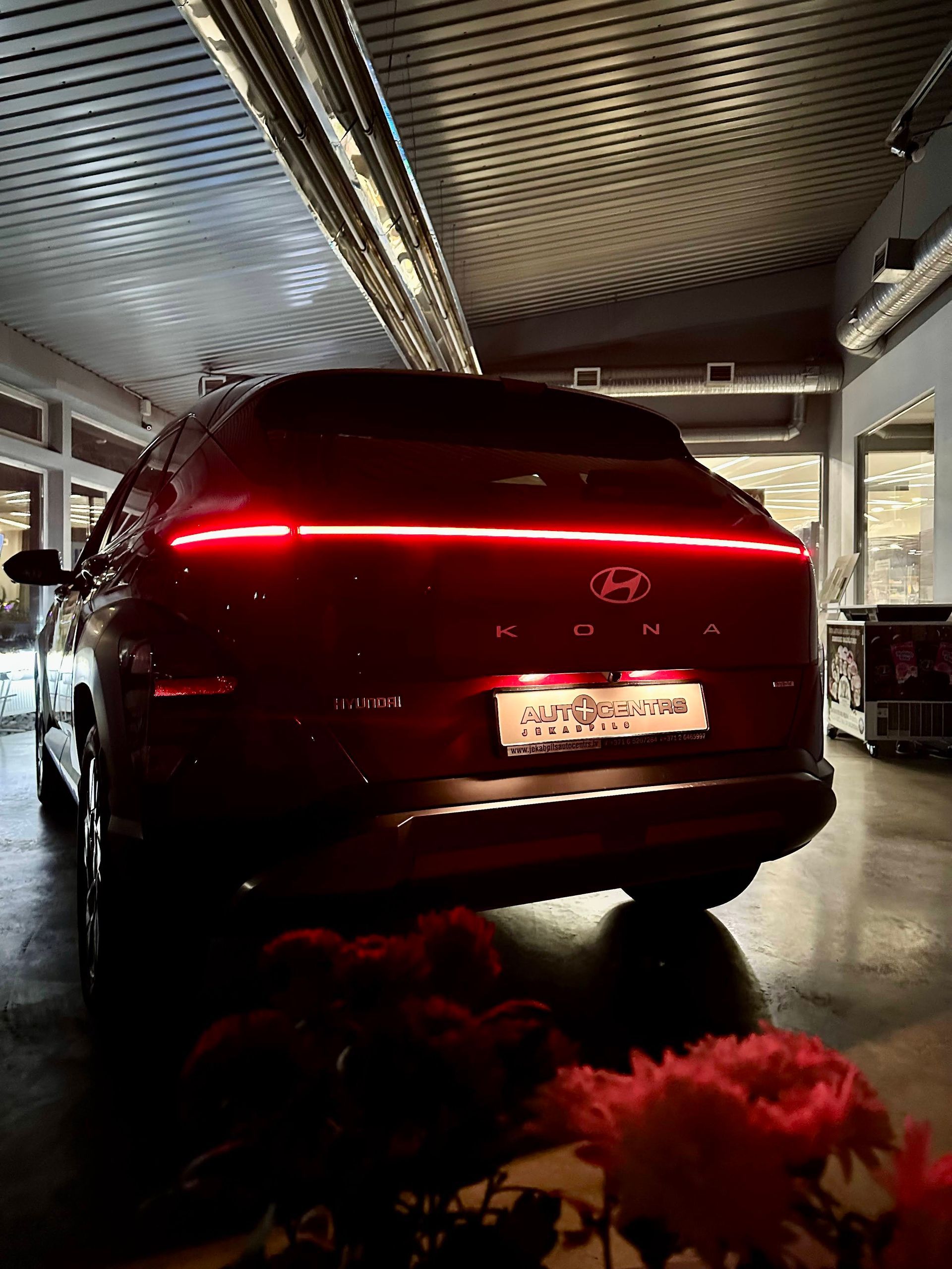 Melna mašīna stāv garāžā pie puķēm.