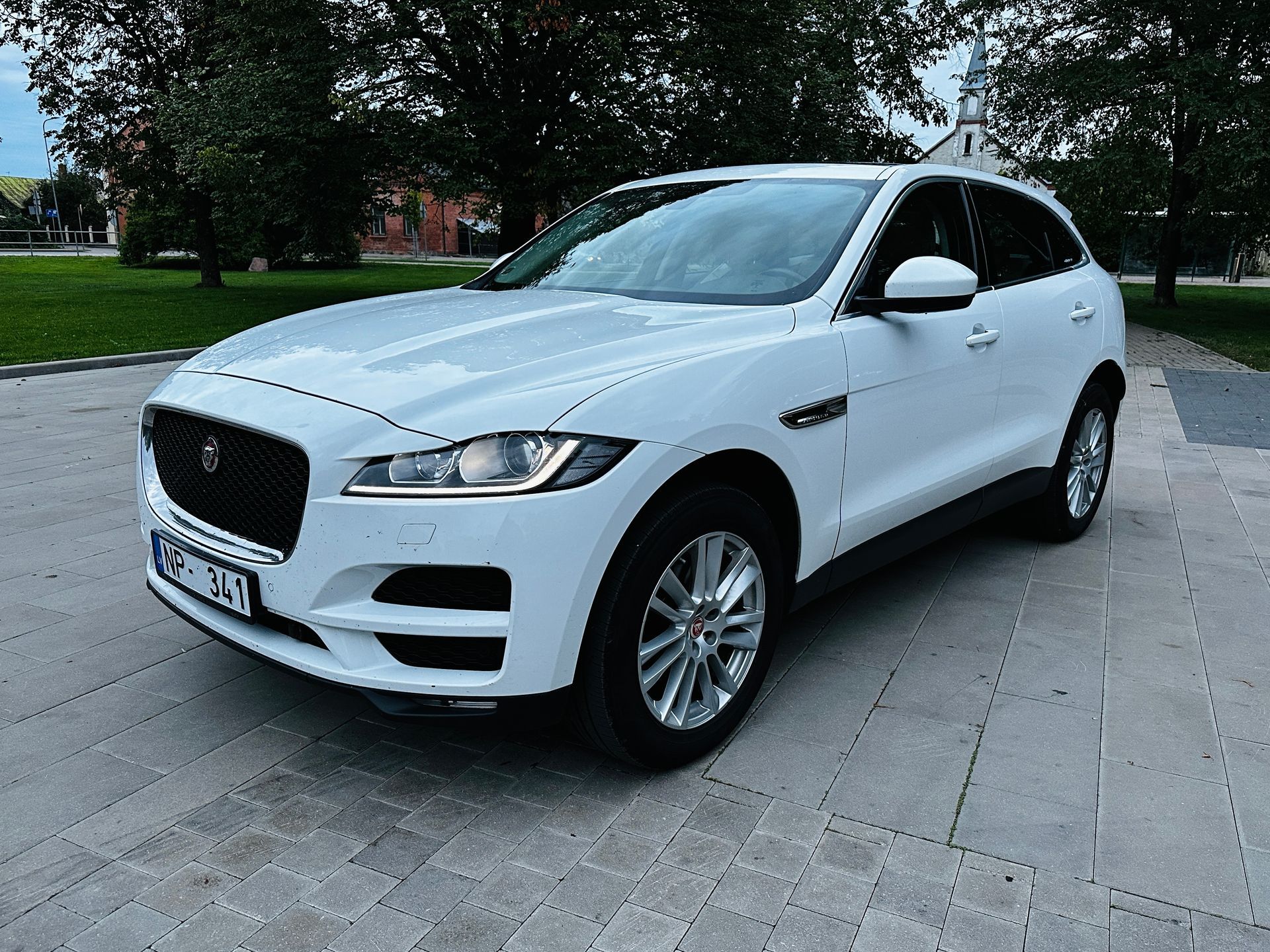 Balts jaguārs f pace ir novietots uz ietves