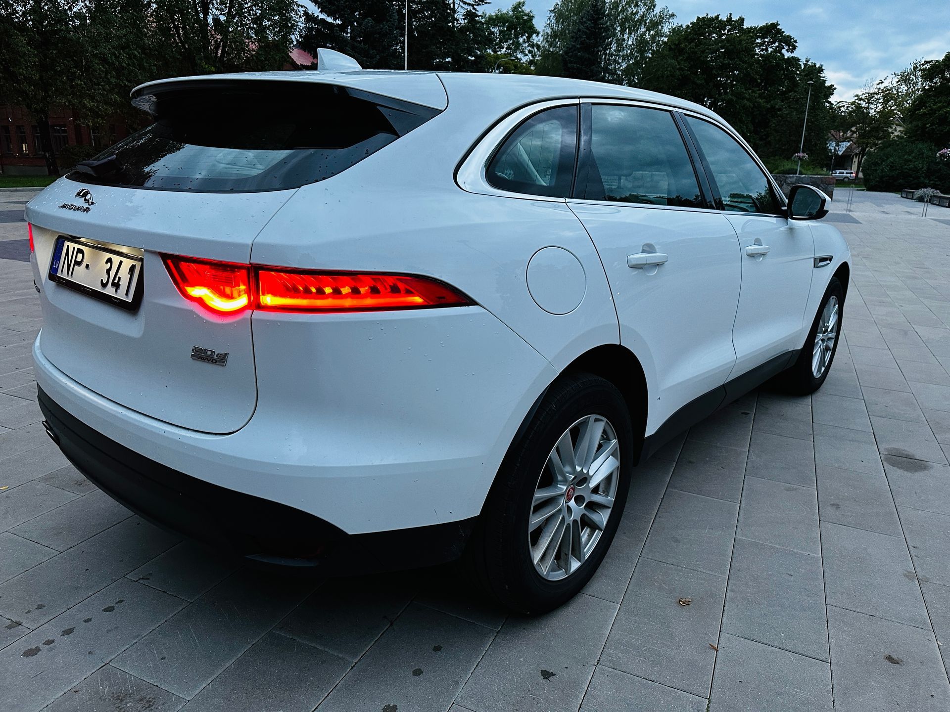 Balts jaguārs f pace ir novietots uz ietves