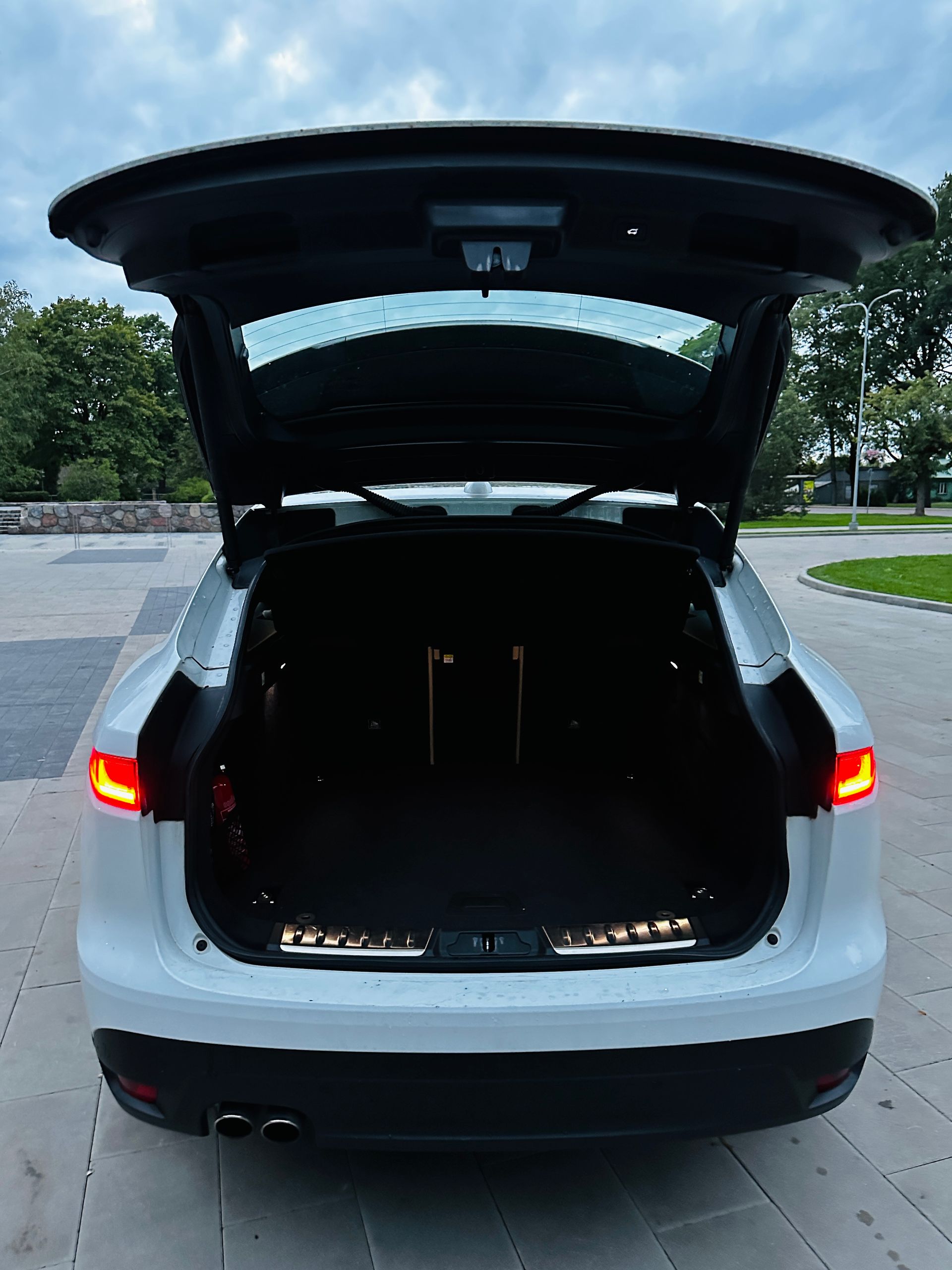 Baltas automašīnas aizmugure ar atvērtu bagāžnieku