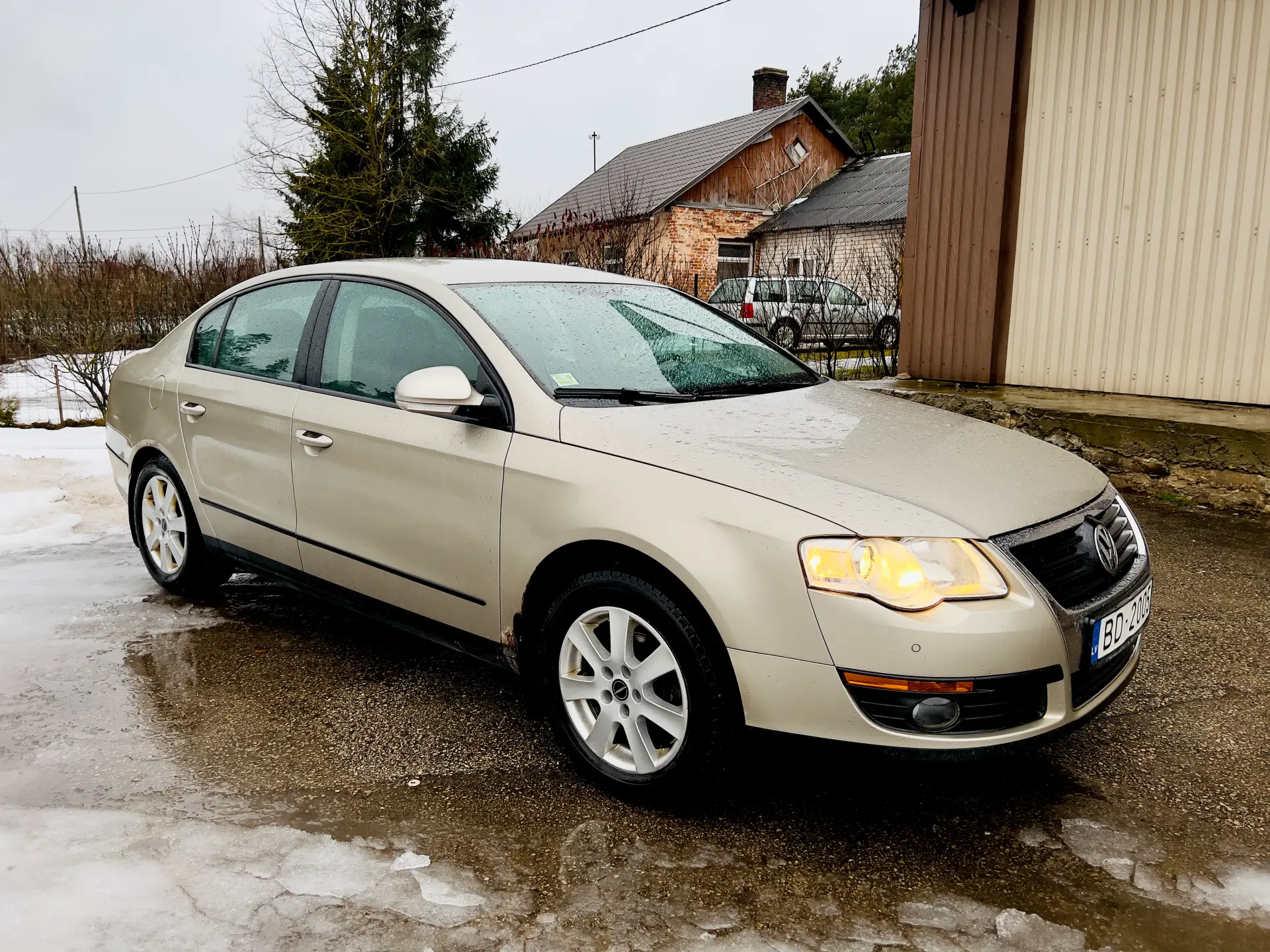 Sudraba krāsas automašīna ir novietota pie ēkas.