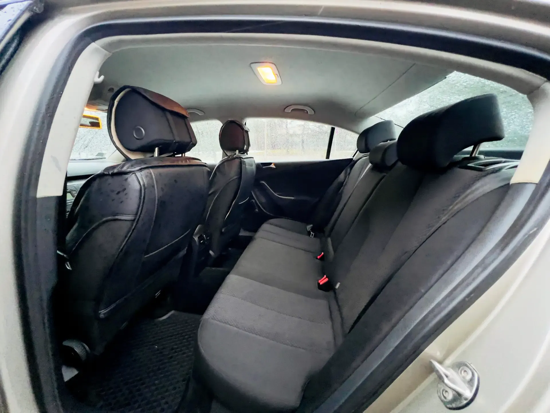 Automašīnas aizmugurējais sēdeklis ar melniem sēdekļiem un galvas balstiem.