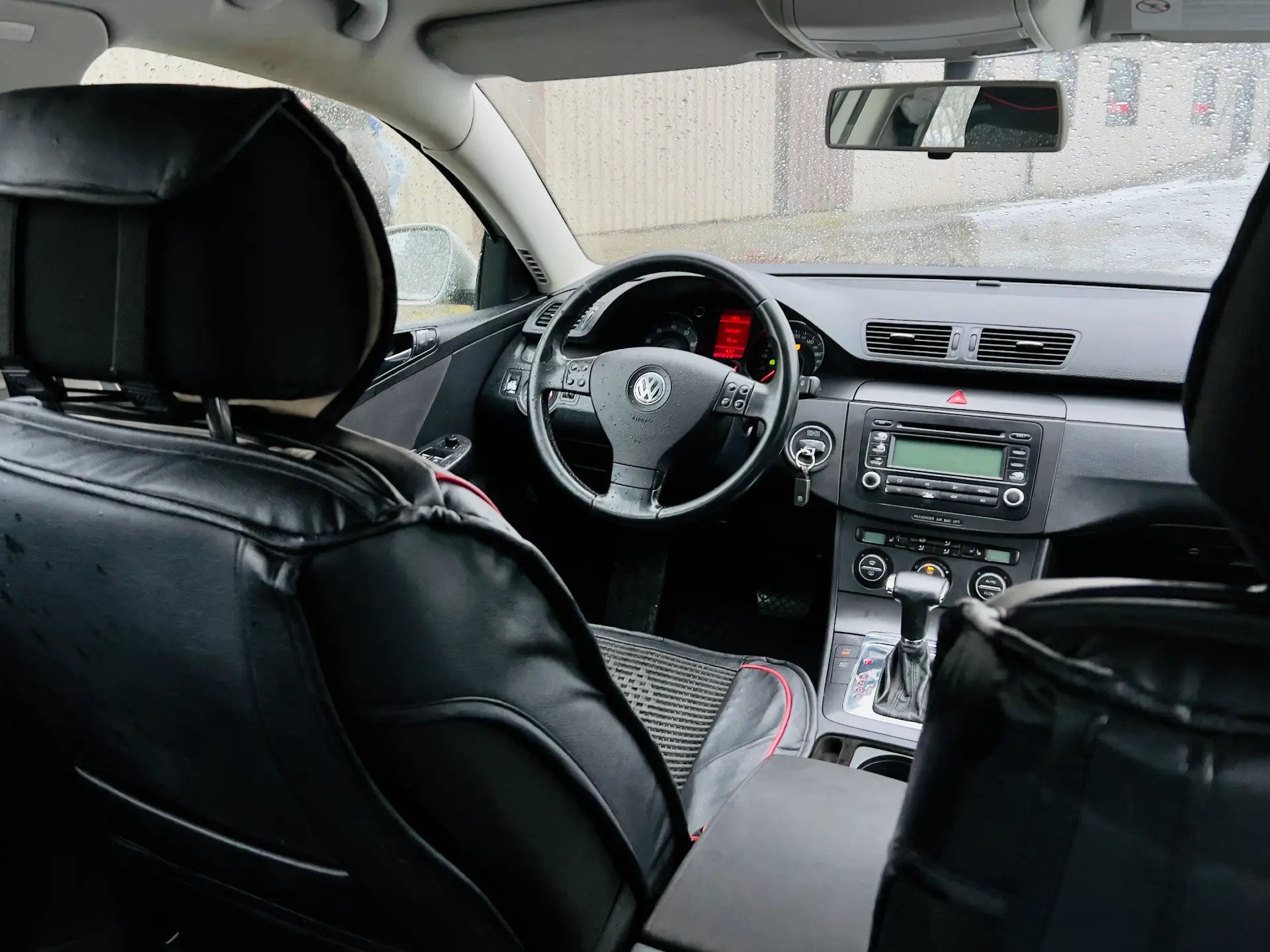 Automašīnas iekšpuse ar melniem sēdekļiem un stūri