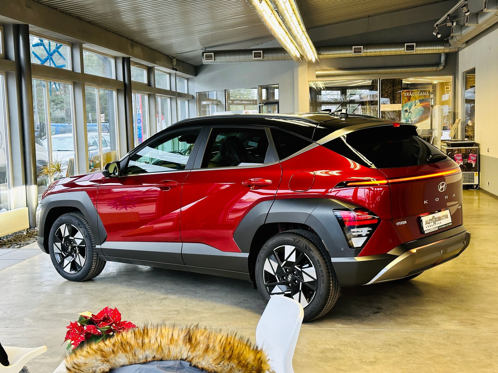 Sarkana mašīna stāv salonā pie vainaga.