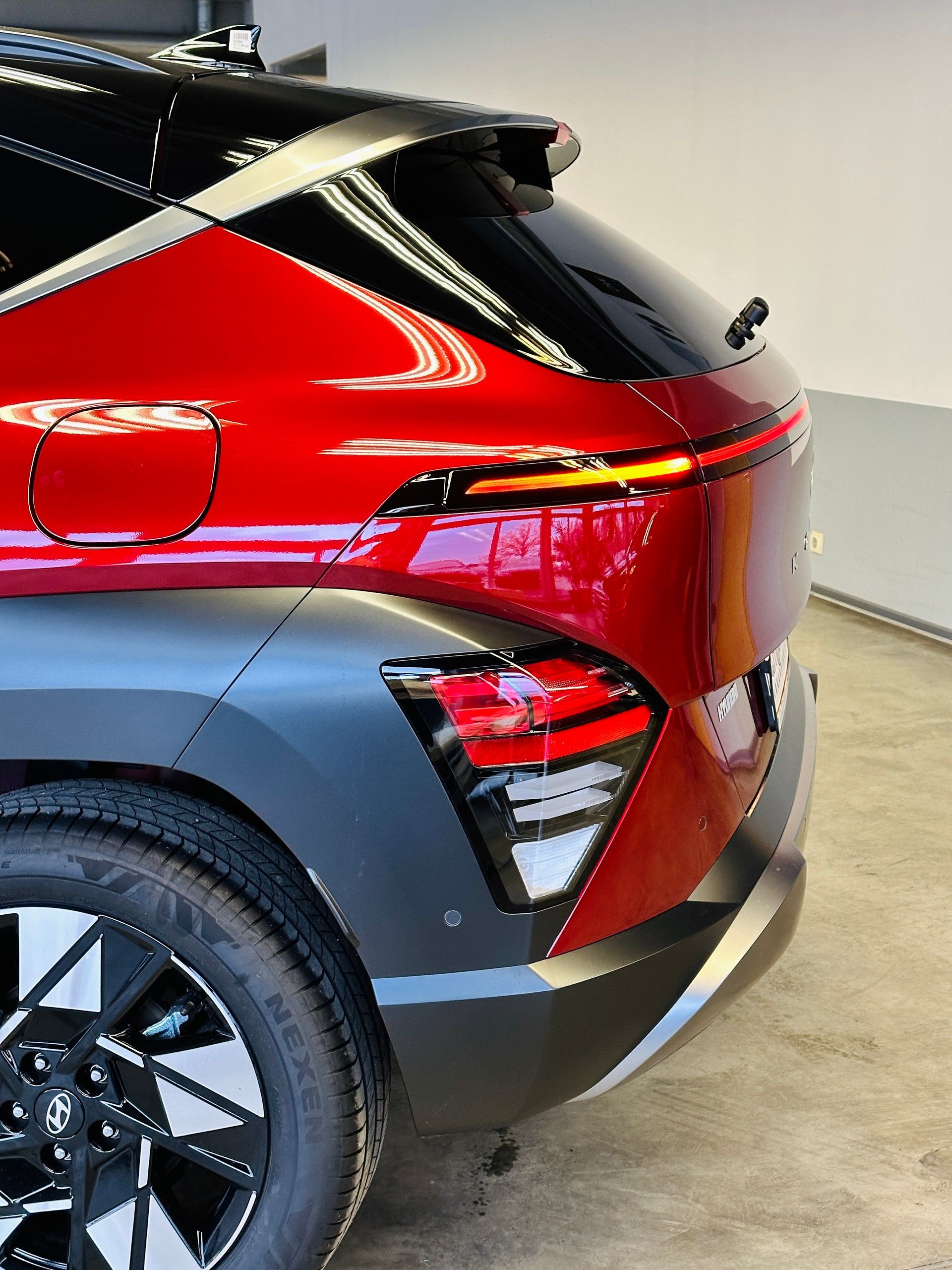 Garāžā stāv sarkana mašīna ar melnu apdari