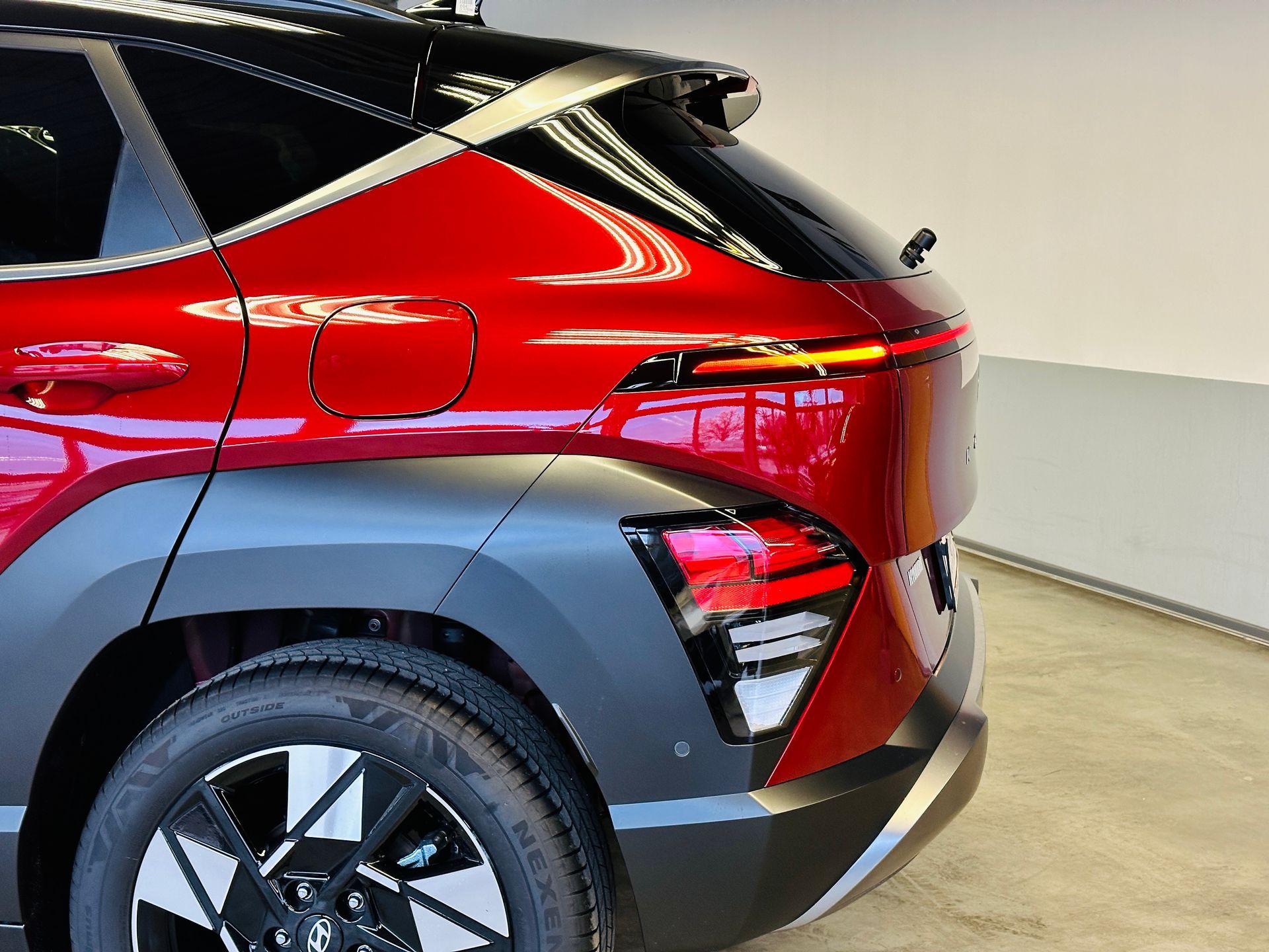 Garāžā stāv sarkana mašīna ar melnu apdari