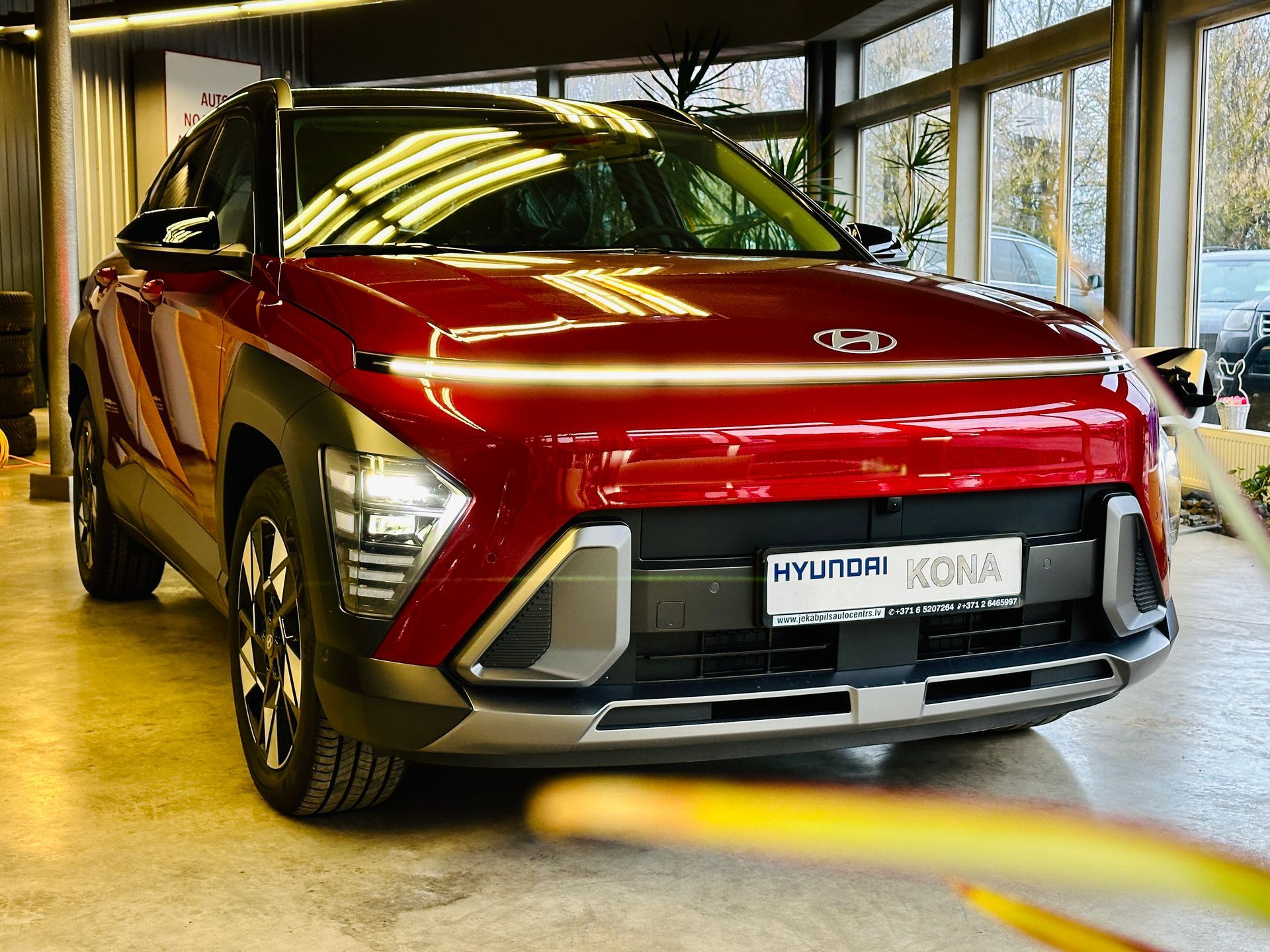 Sarkana hyundai kona ir novietota izstāžu zālē.