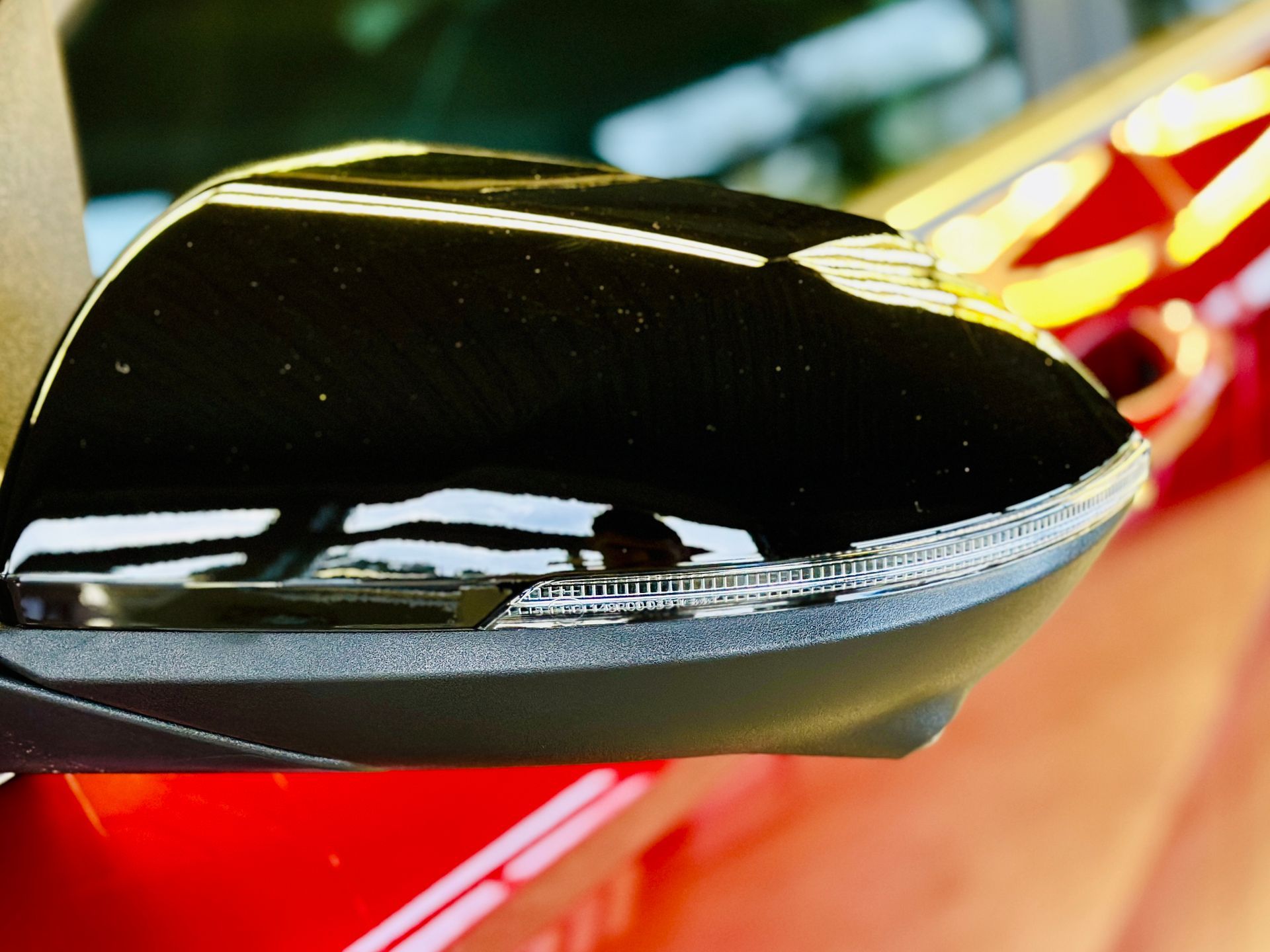 Sānu spoguļa tuvplāns uz sarkanas automašīnas