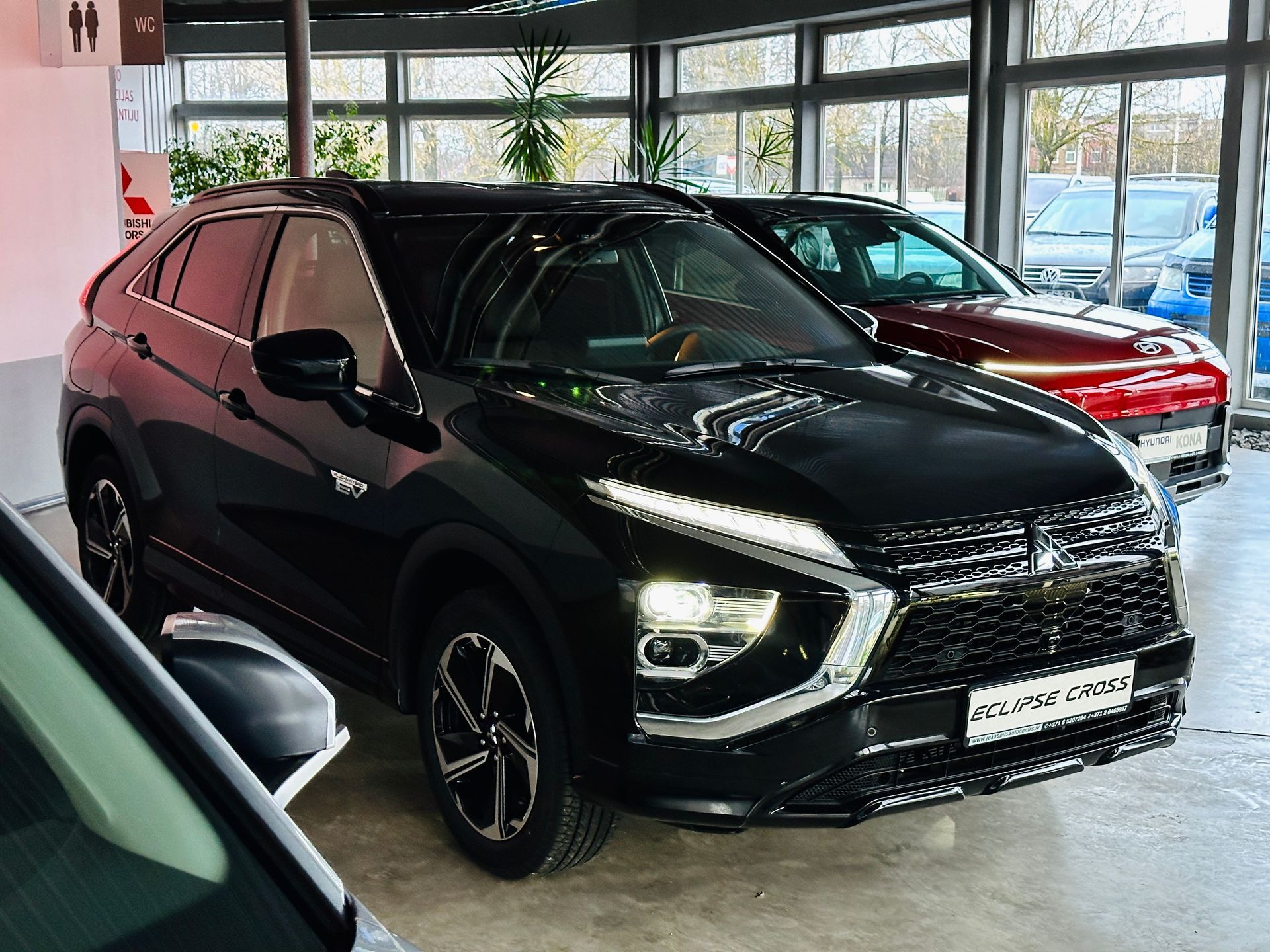 Melna automašīna ir novietota salonā ar citām automašīnām.