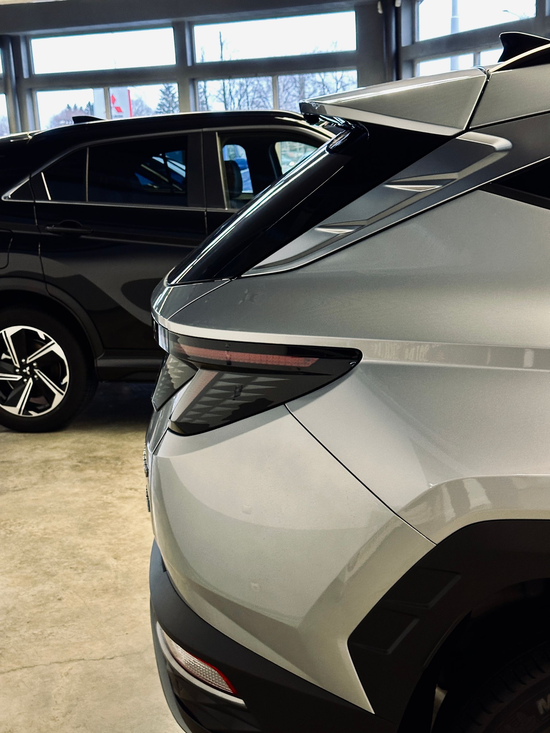 Divas automašīnas ir novietotas blakus viena otrai salonā