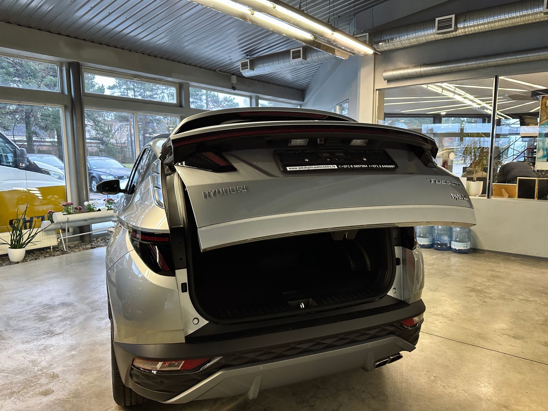 Sudraba krāsas auto bagāžnieks ir atvērts salonā.