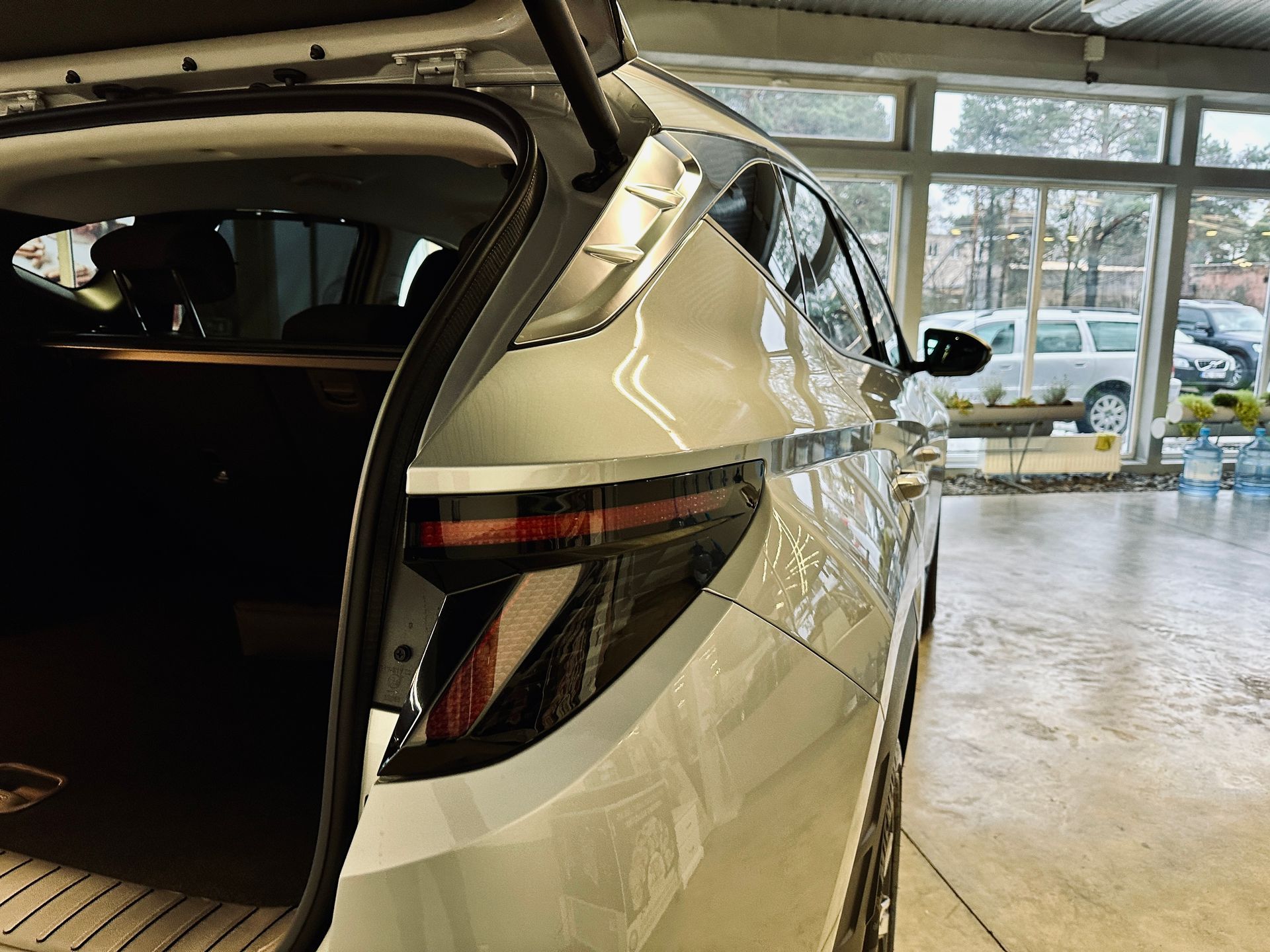 Balta mašīna stāv garāžā ar atvērtu bagāžnieku