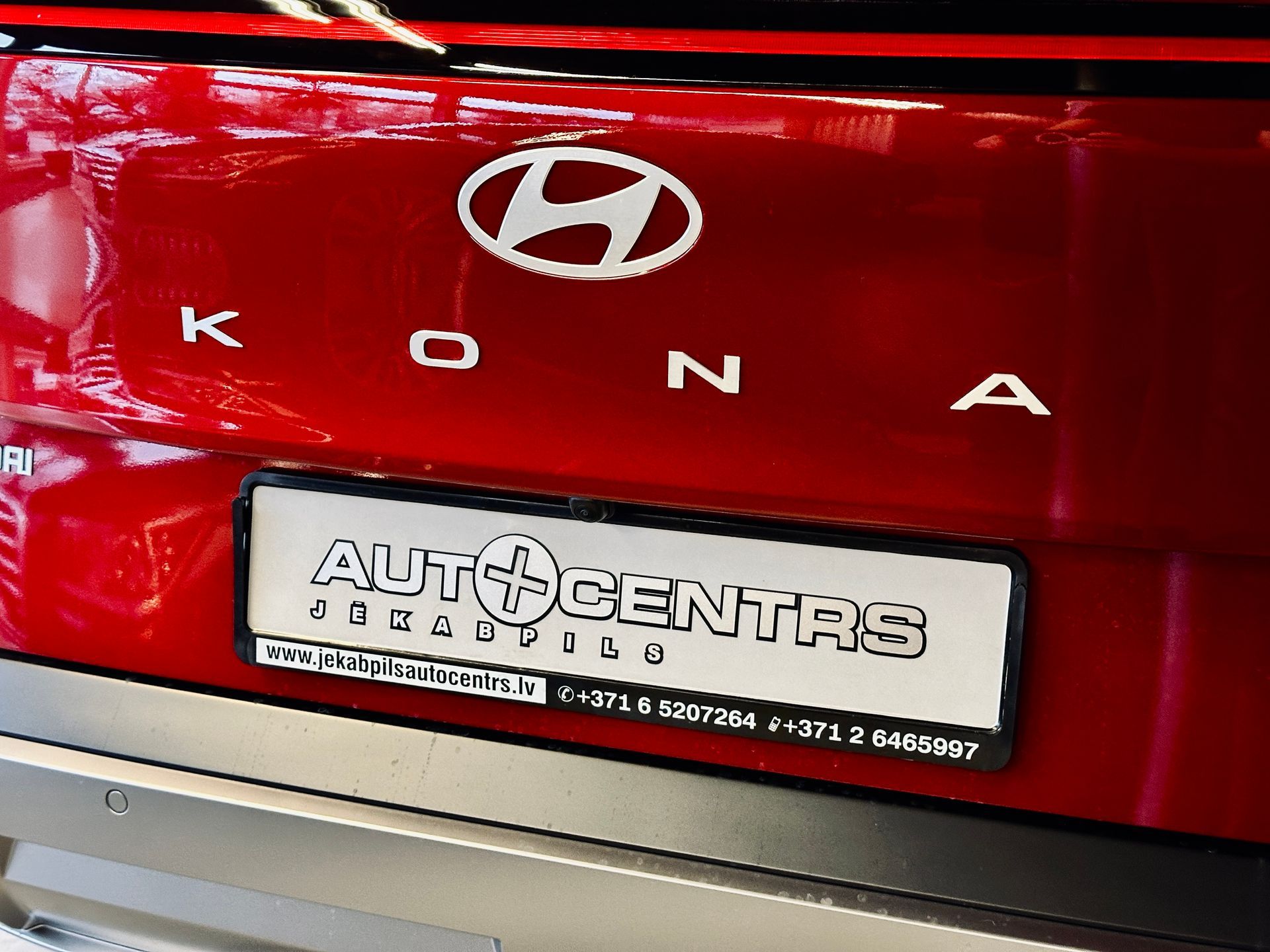 Sarkana hyundai kona ar numura zīmi, kurā rakstīts auto centras