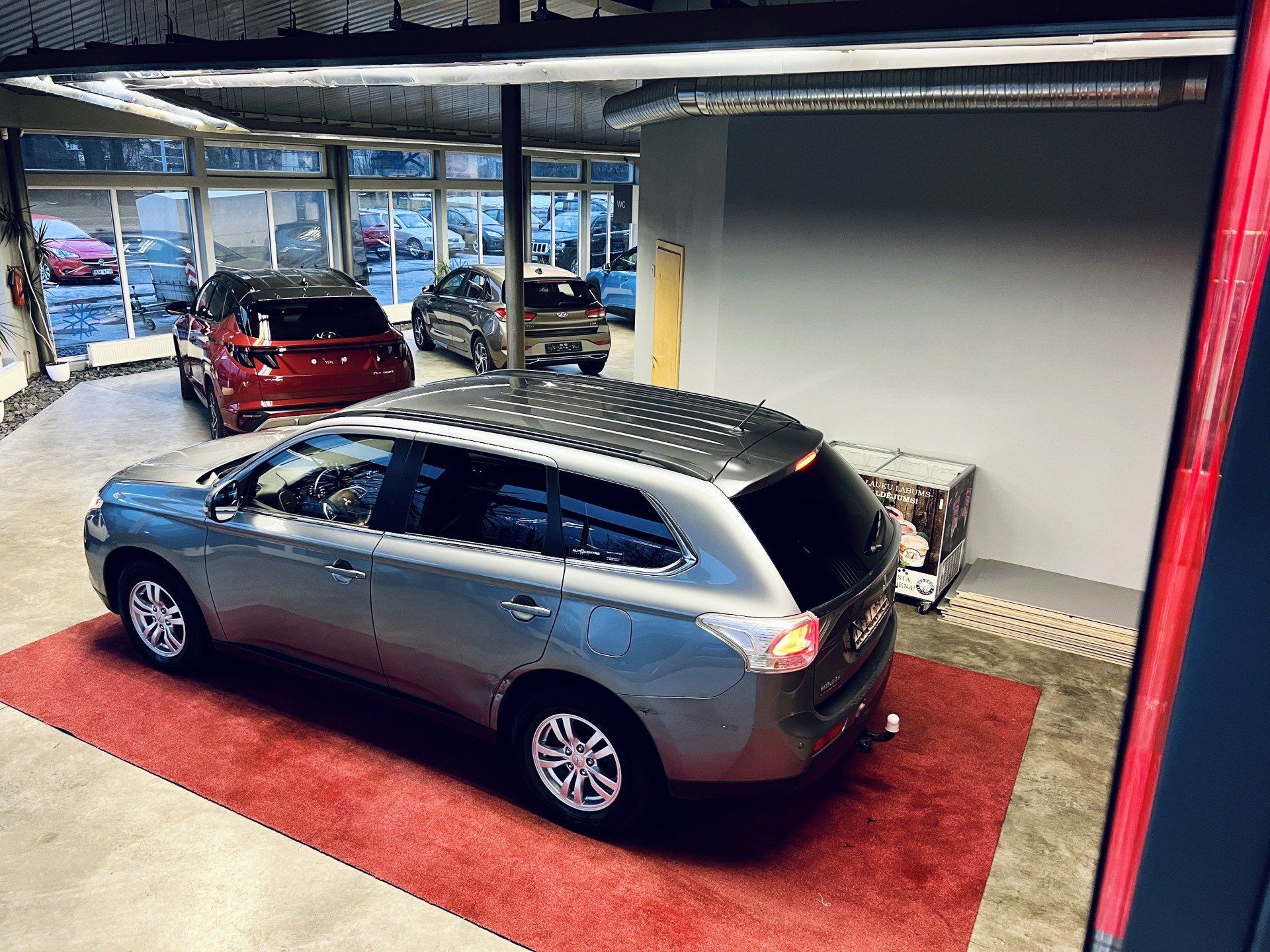 Pelēks apvidus auto ir novietots uz sarkana paklāja izstāžu zālē.