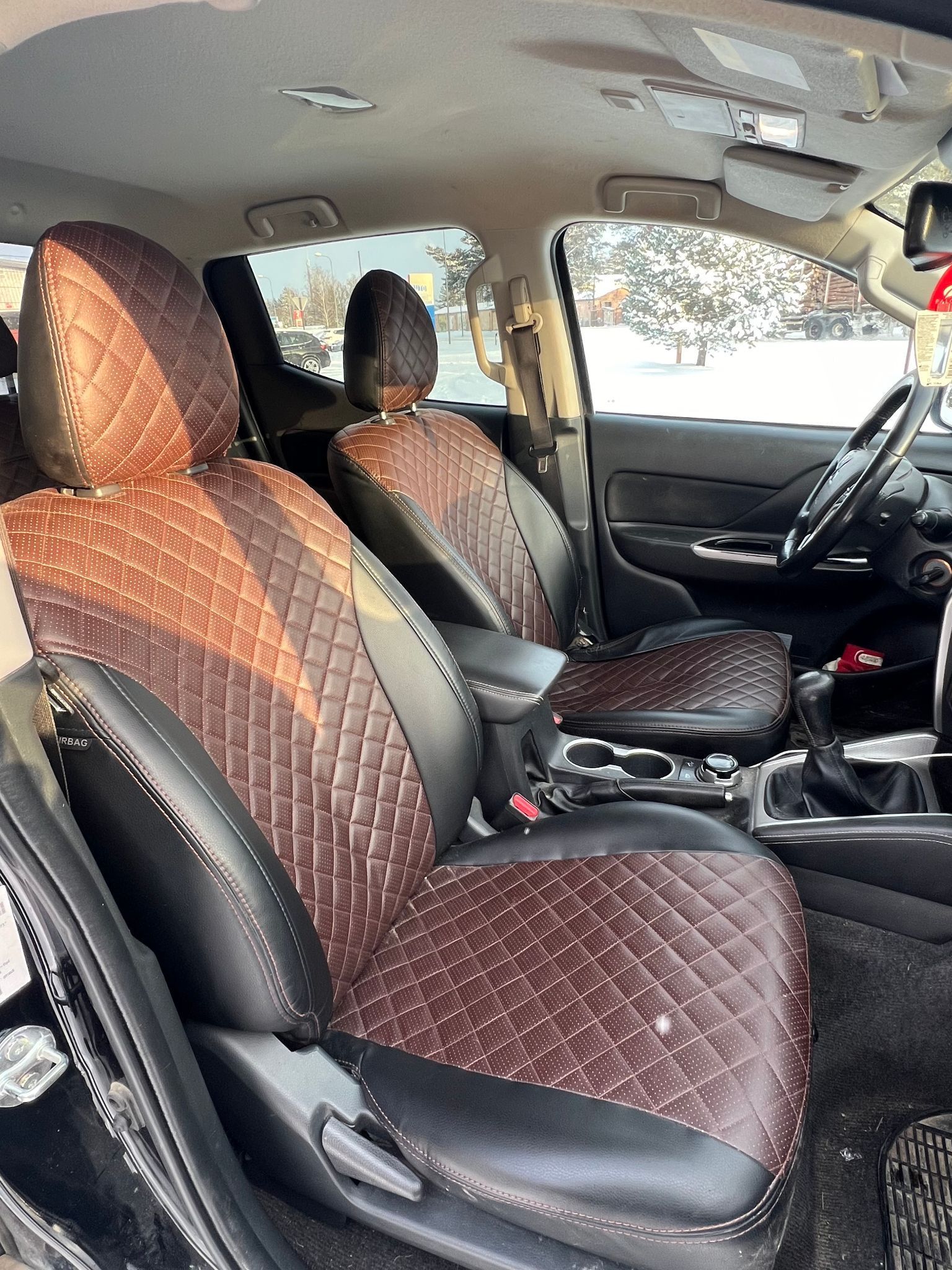 Automašīnas salons ar brūniem un melniem sēdekļu pārvalkiem.