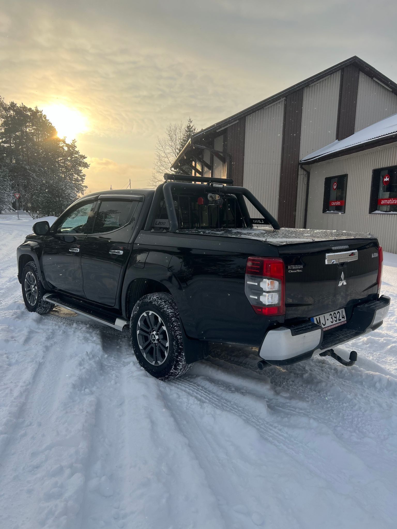 Melna kravas automašīna ir novietota sniegā pie ēkas.