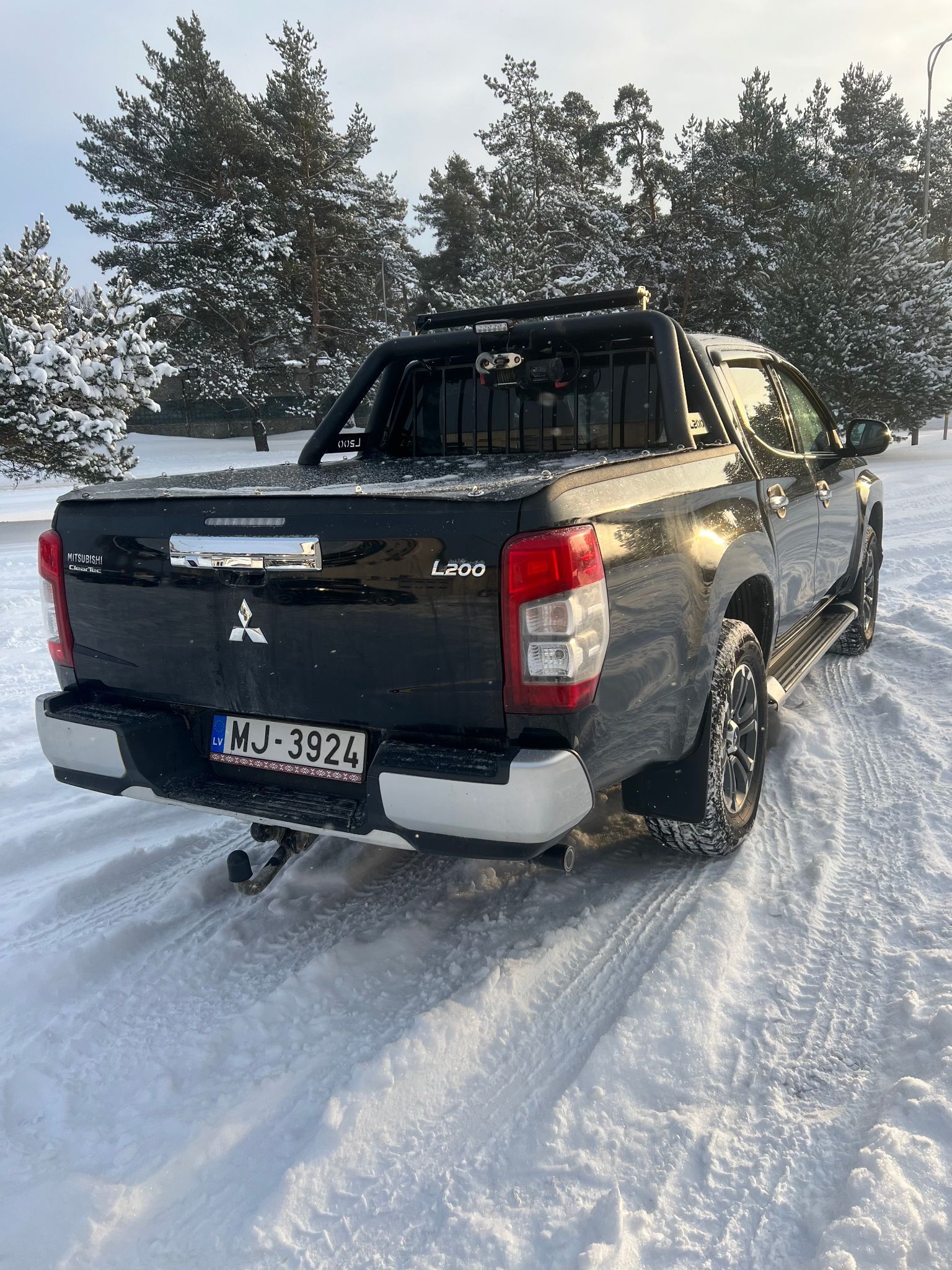 Melns pikaps stāv sniegā.