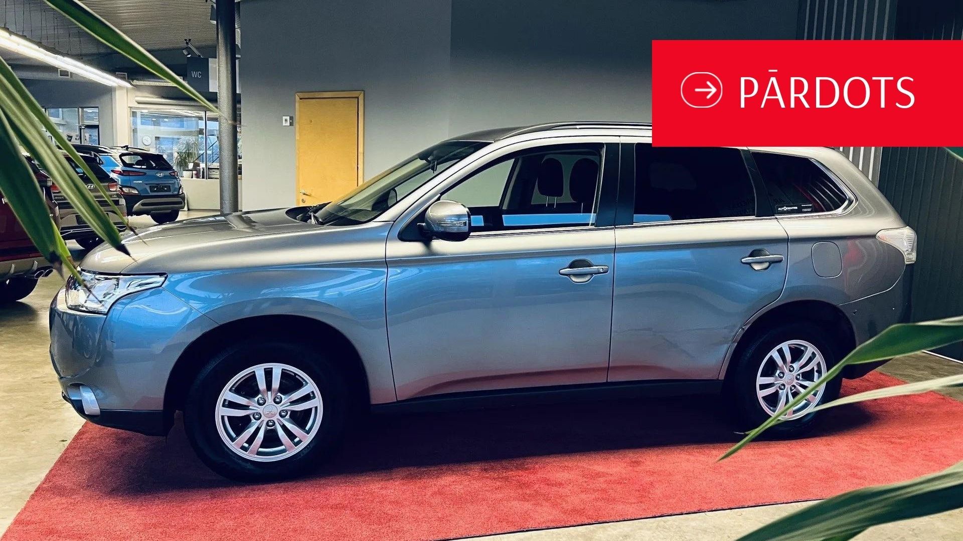 Sudraba apvidus auto ir novietots izstāžu zālē pie sarkana paklāja.