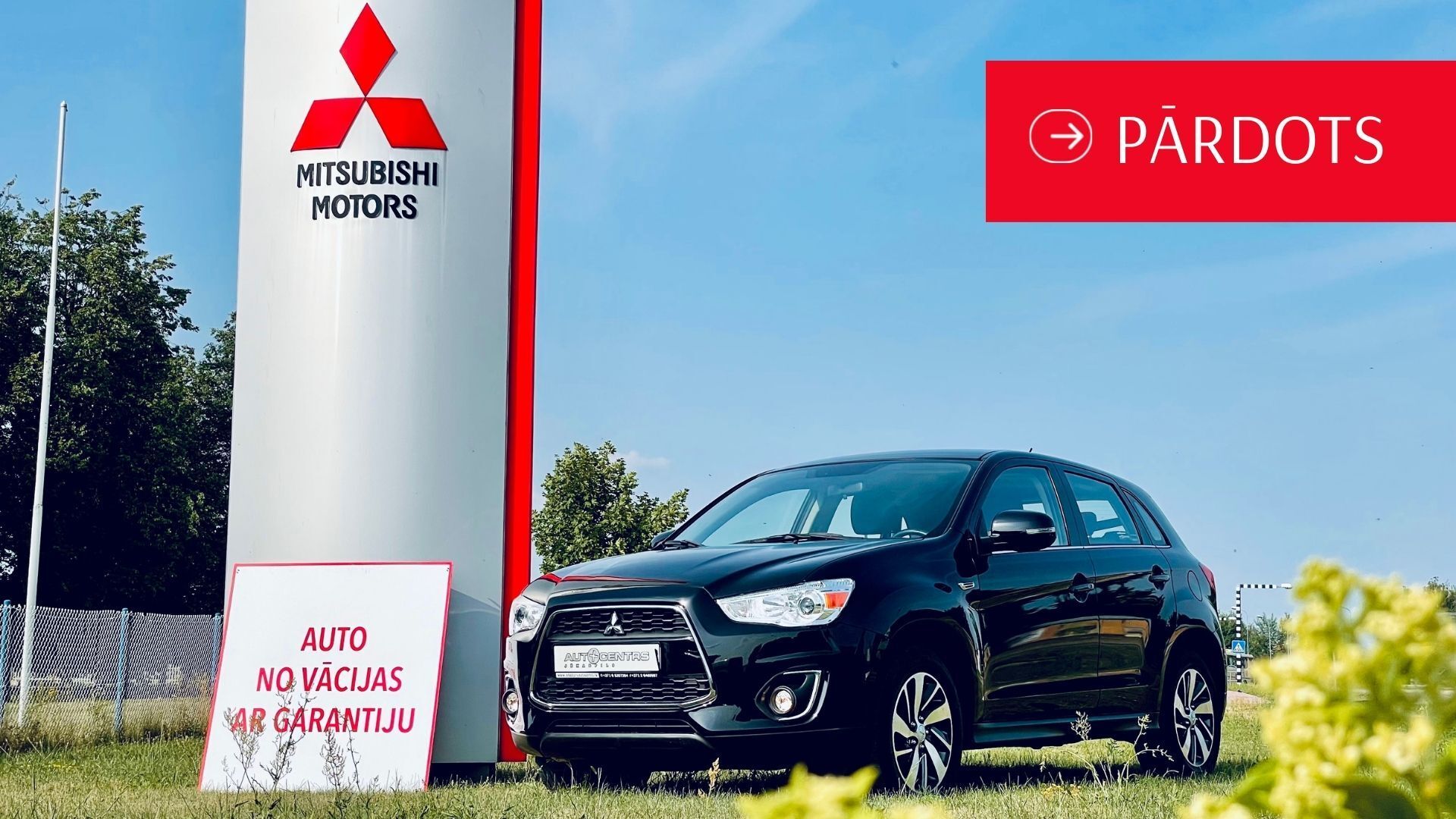 Melna automašīna ir novietota pie mitsubishi motors zīmes.