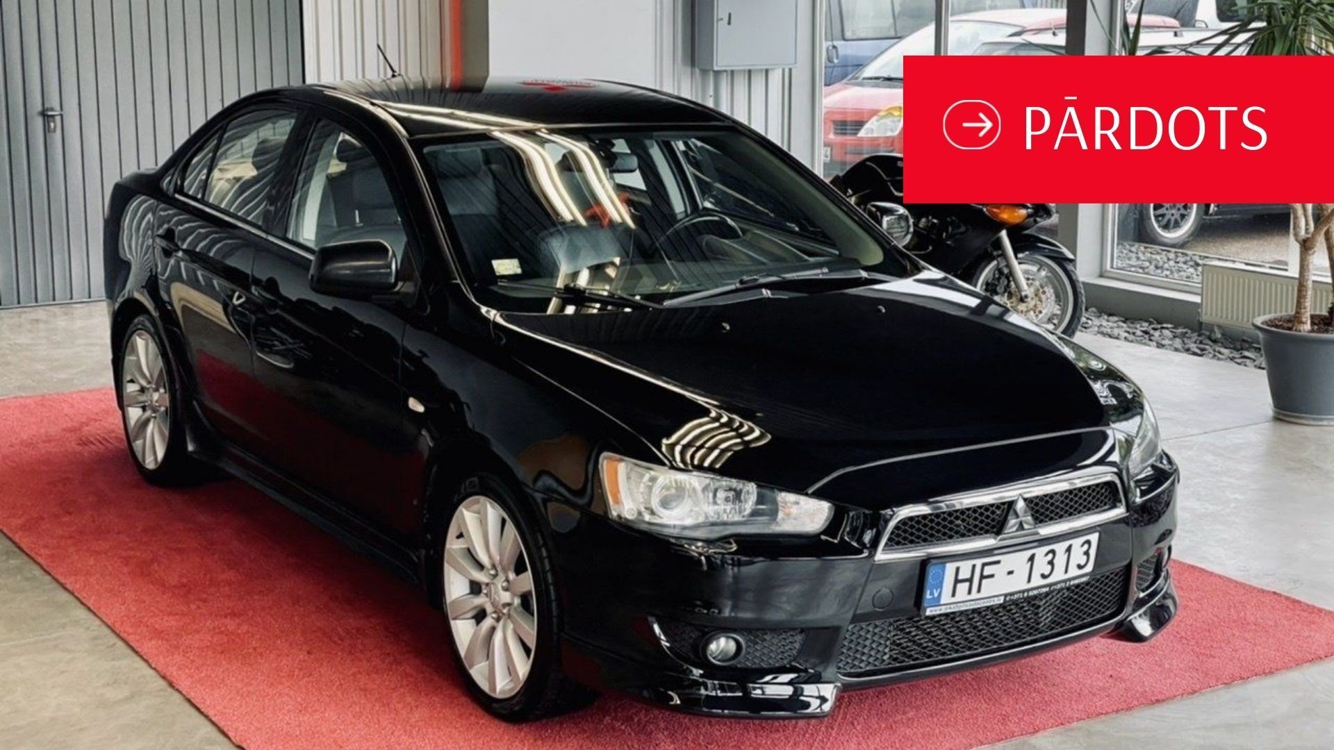 Melna mašīna sēž uz sarkana paklāja salonā.