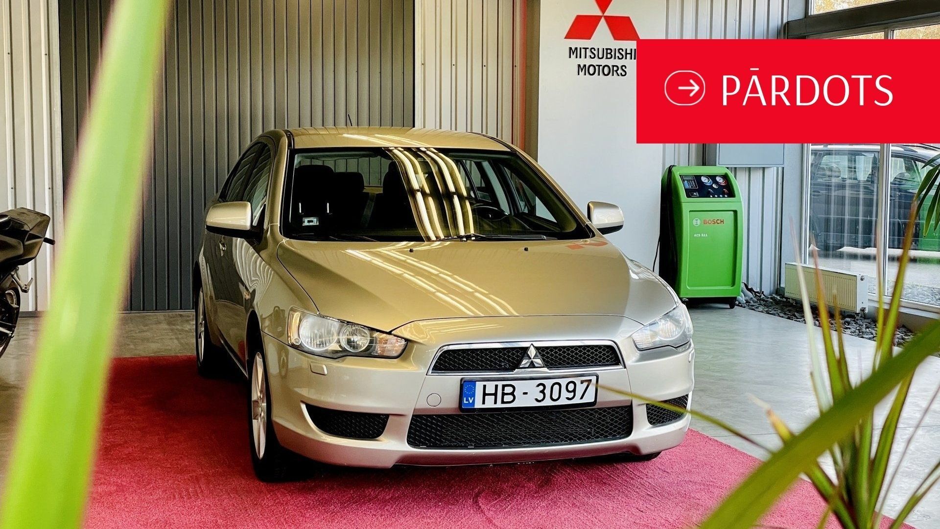 Sudrabainā mitsubishi automašīna ir novietota salonā.
