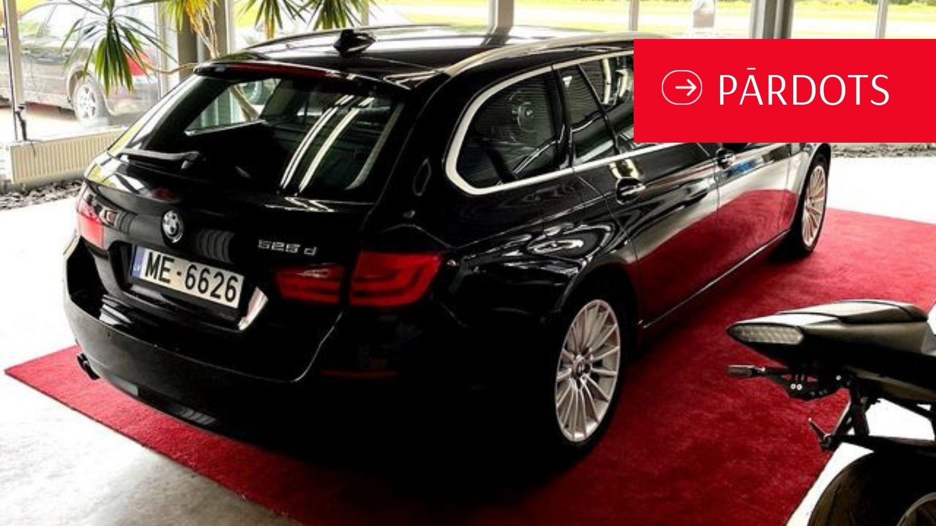 Melns bmw stāv salonā uz sarkanā paklāja.