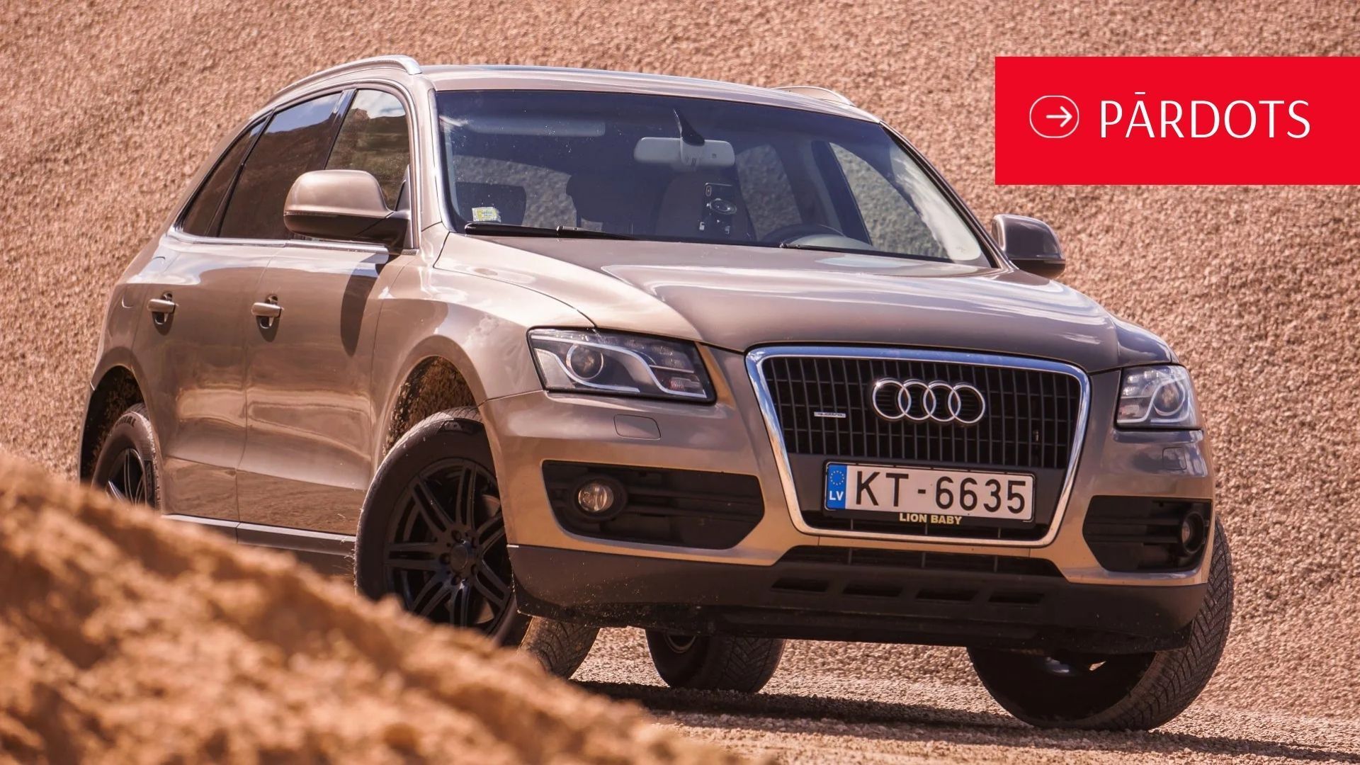Audi q5 stāv netīrumu kalna galā.