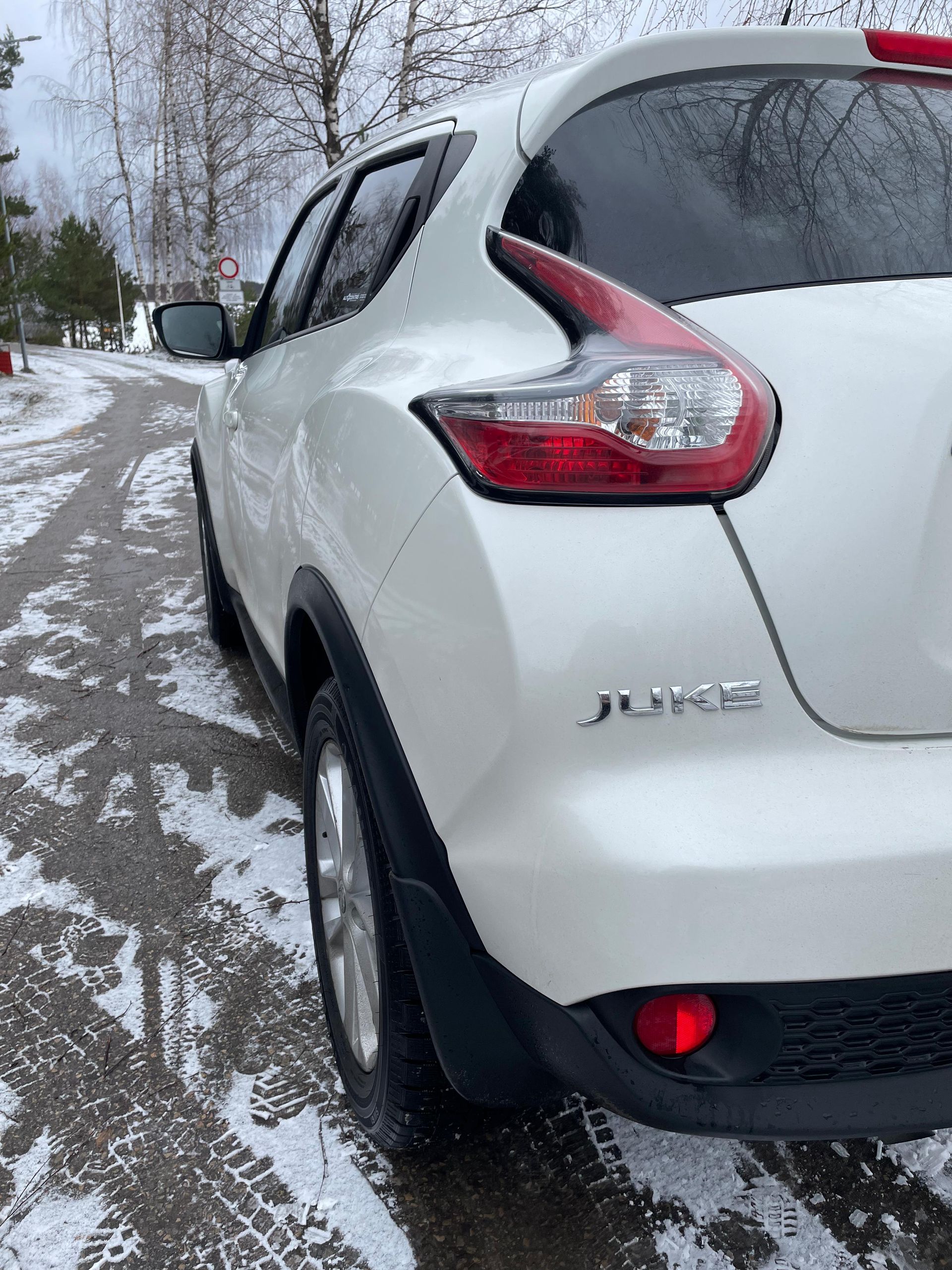 Uz sniegota ceļa stāv balta mašīna.