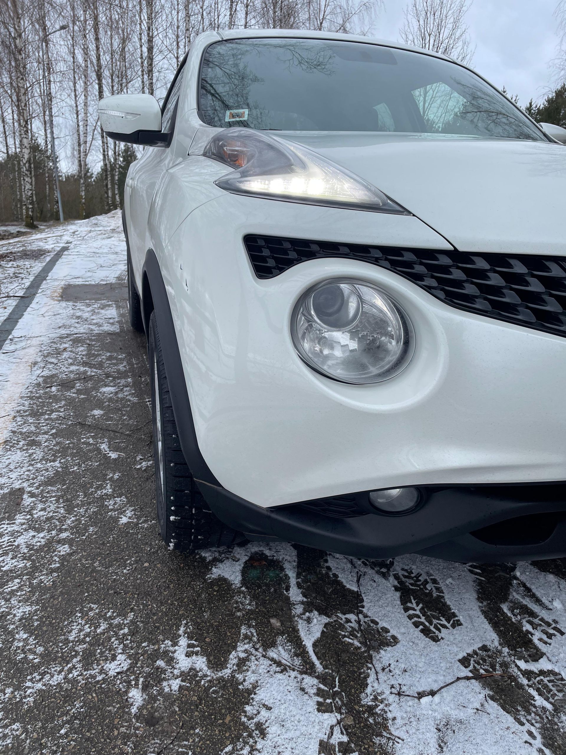 Stāvlaukumā sniegā stāv balta mašīna.