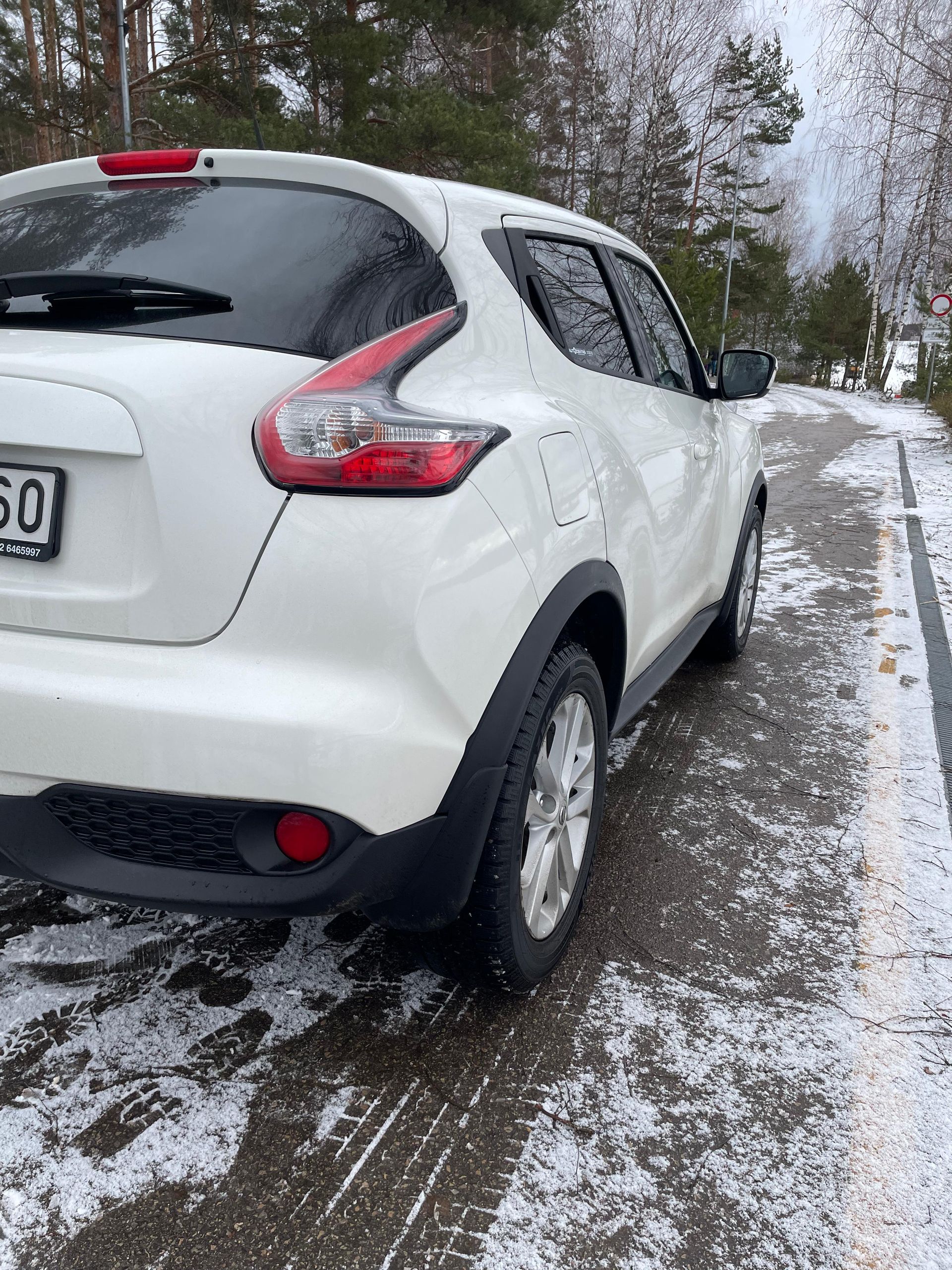 Uz sniegota ceļa stāv balta mašīna.