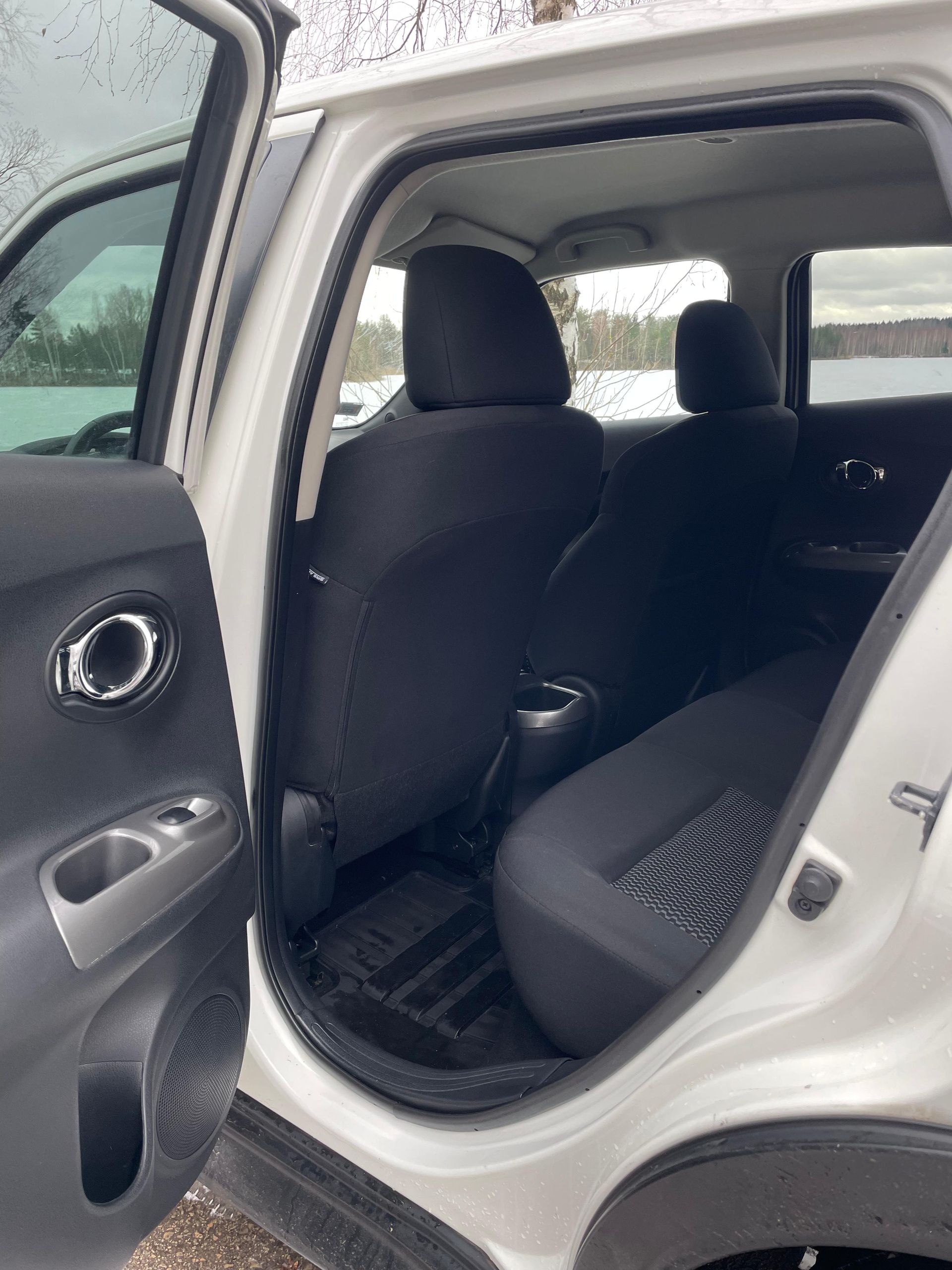 Baltas automašīnas aizmugurējais sēdeklis ar atvērtām durvīm.