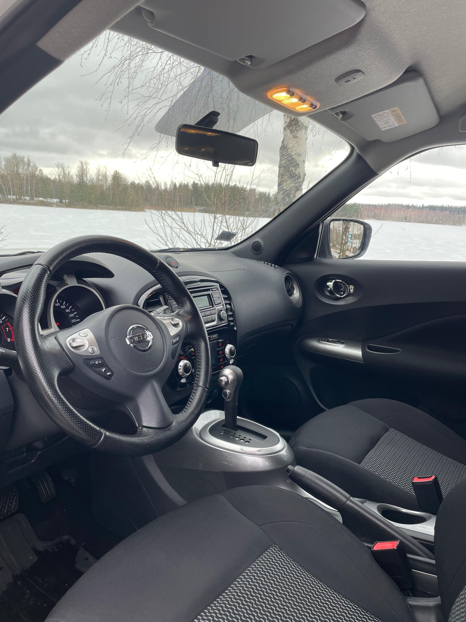 Automašīnas iekšpuse ar stūri un atpakaļskata spoguli.